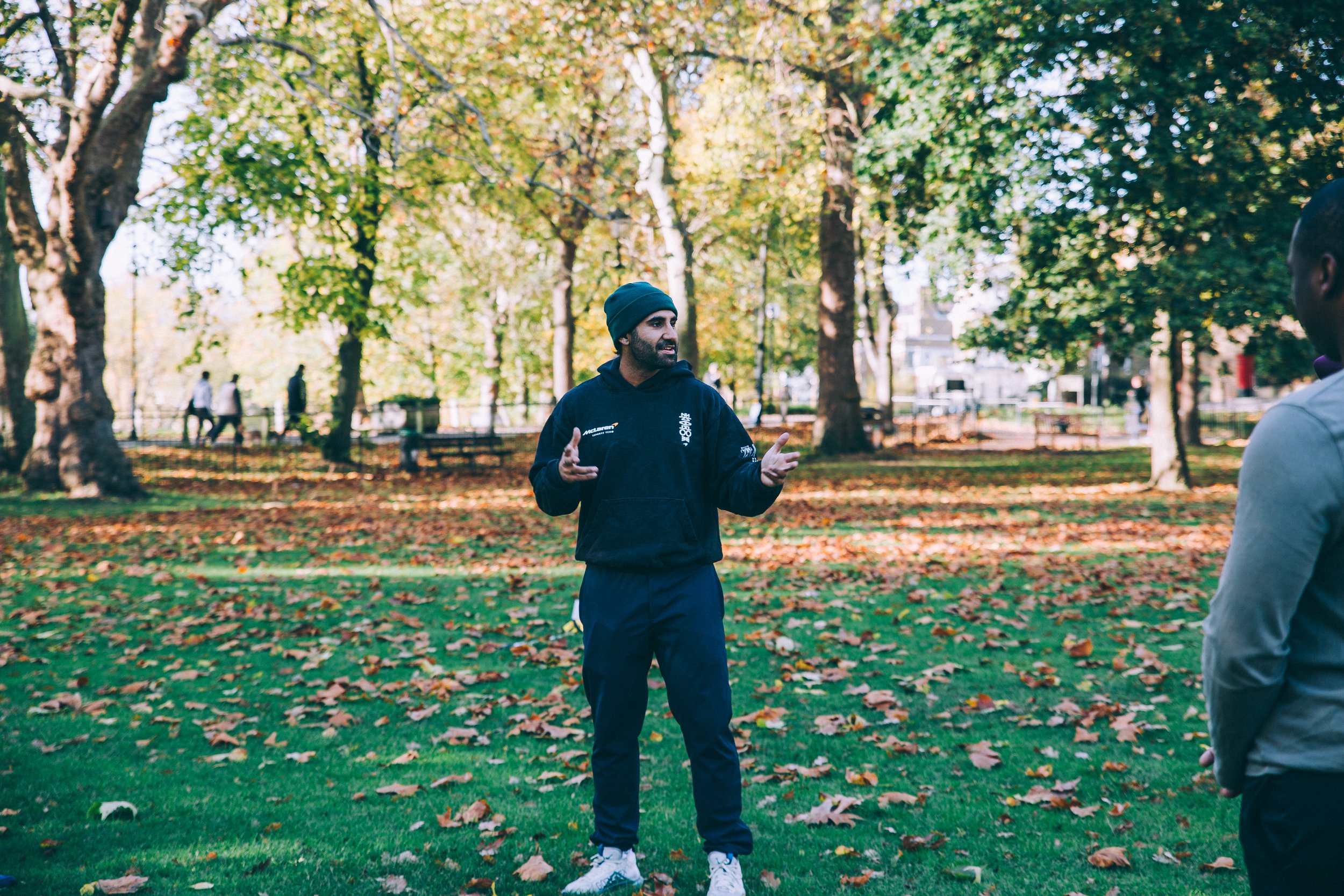 wild LDN group coach explaining the outdoor fitness workout plan in Highbury Fields, Islington in a beautiful location