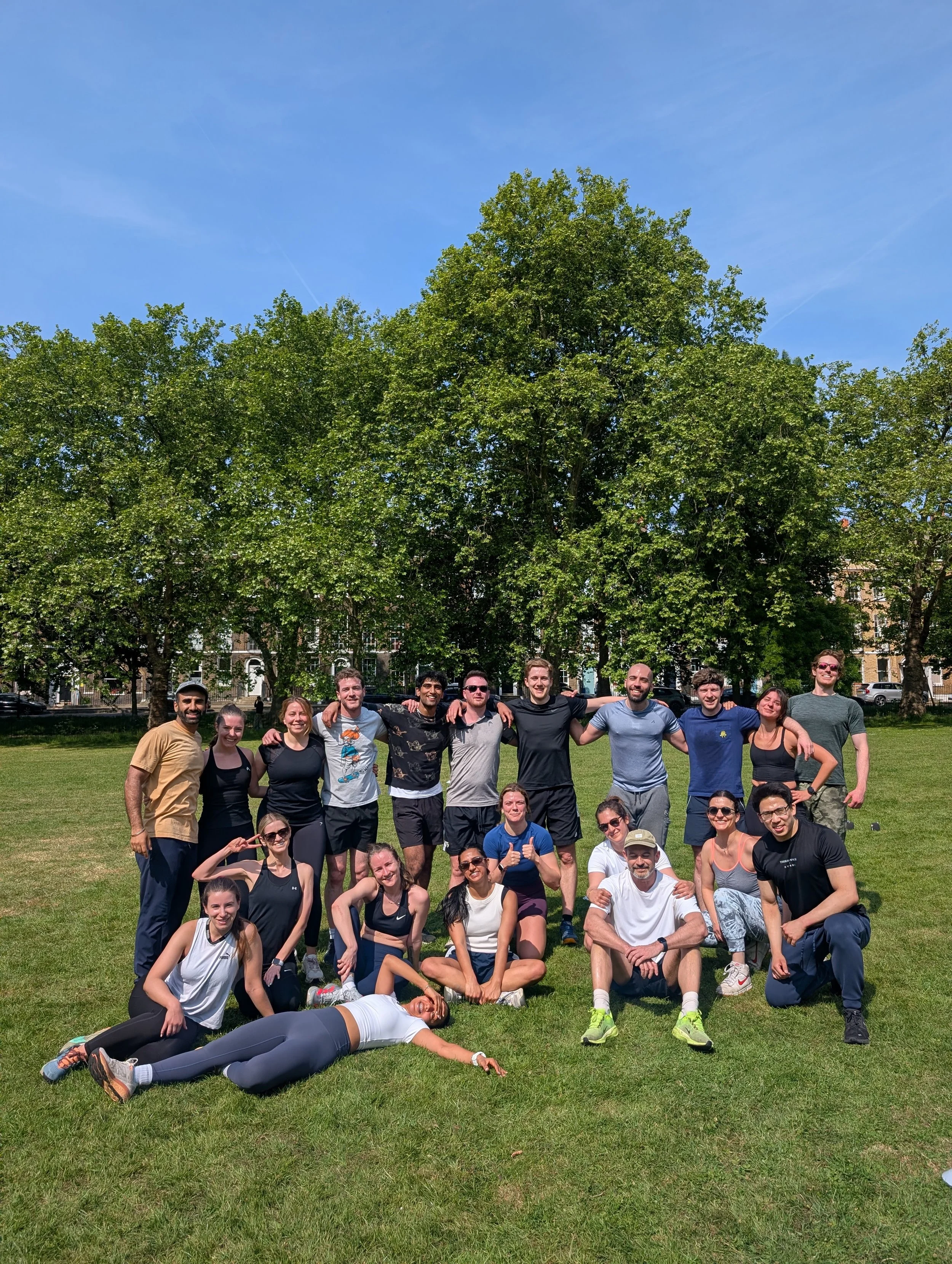 post workout from wild LDN in Highbury Fields, Islington - a group of young, athletic people sweaty and very happy after the outdoor fitness group class in a beautiful London park on a stunning, blue sky summers day