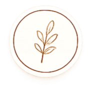 A circular emblem featuring a simple, stylized plant with leaves in a gold or bronze color.