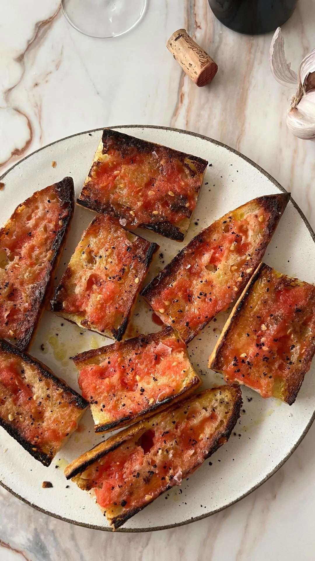 Rebanadas de pan de ajo con salsa de tomate, con carbón en los bordes, en un plato blanco