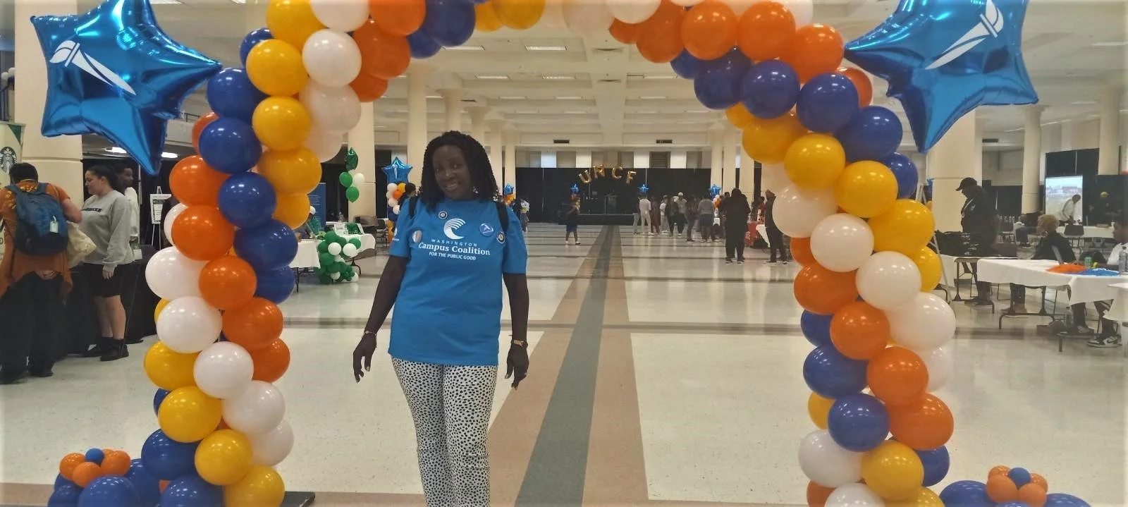 Photo of a WACC volunteer underneath a balloon arch.