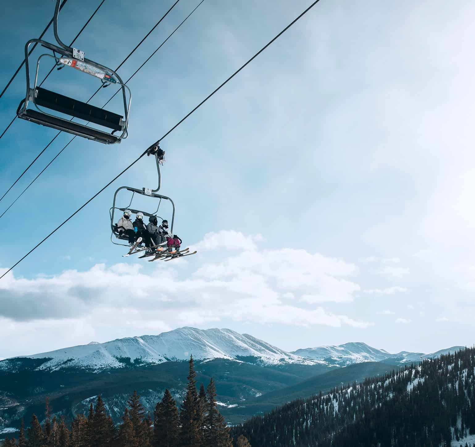 A group of 4 skiers riding a chair lift in Breckenridge, Colorado