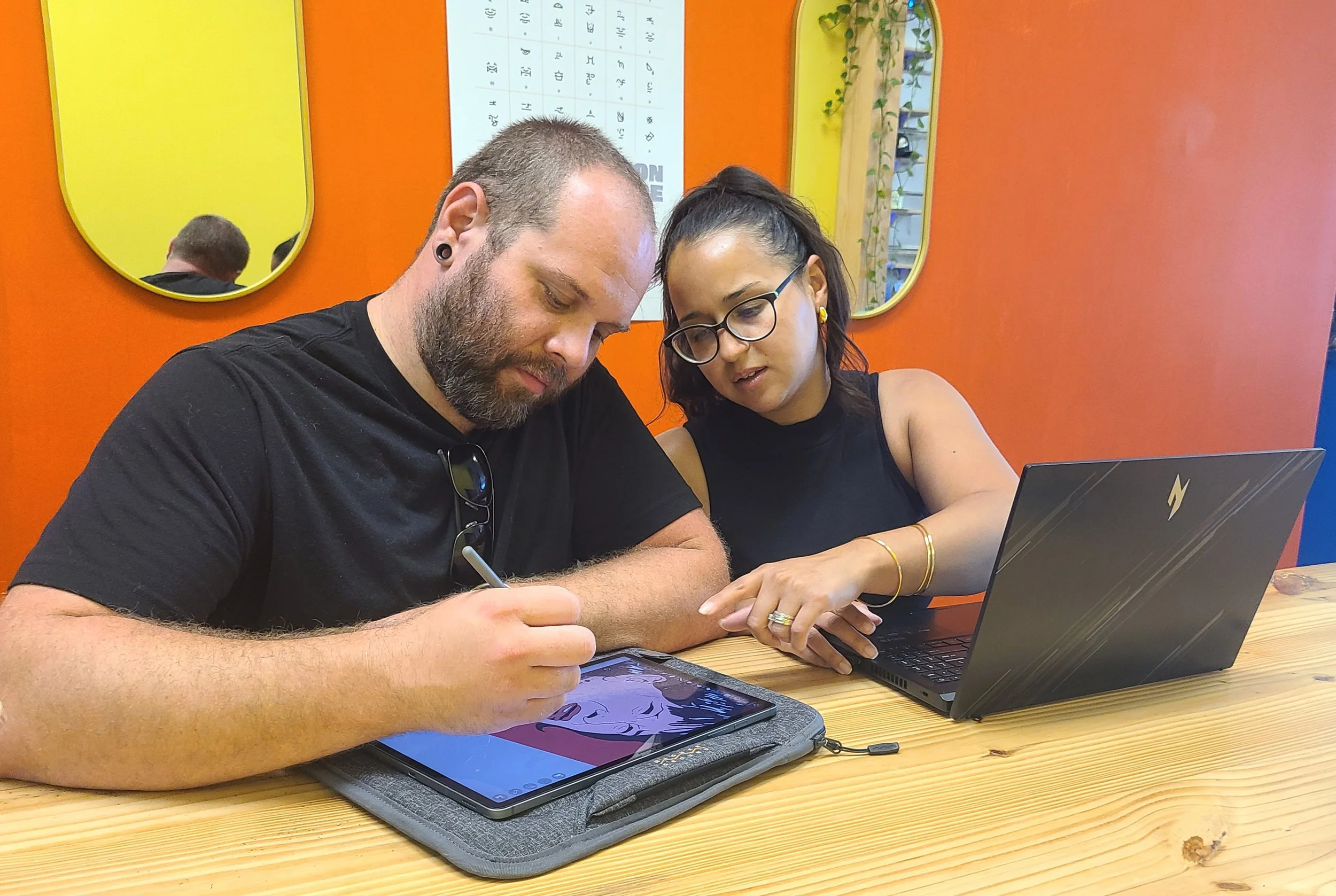 Man and woman sitting in front of a computer together with an orange background