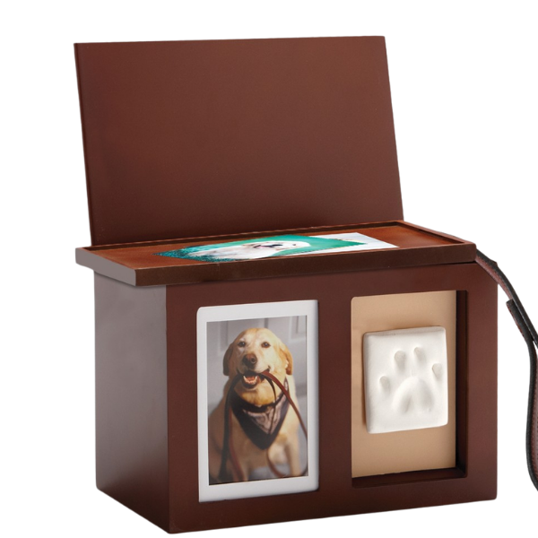 A brown wooden pet remembrance box with a picture of a dog on the front, a paw-shaped cavity, and a lid open showing a photo inside.