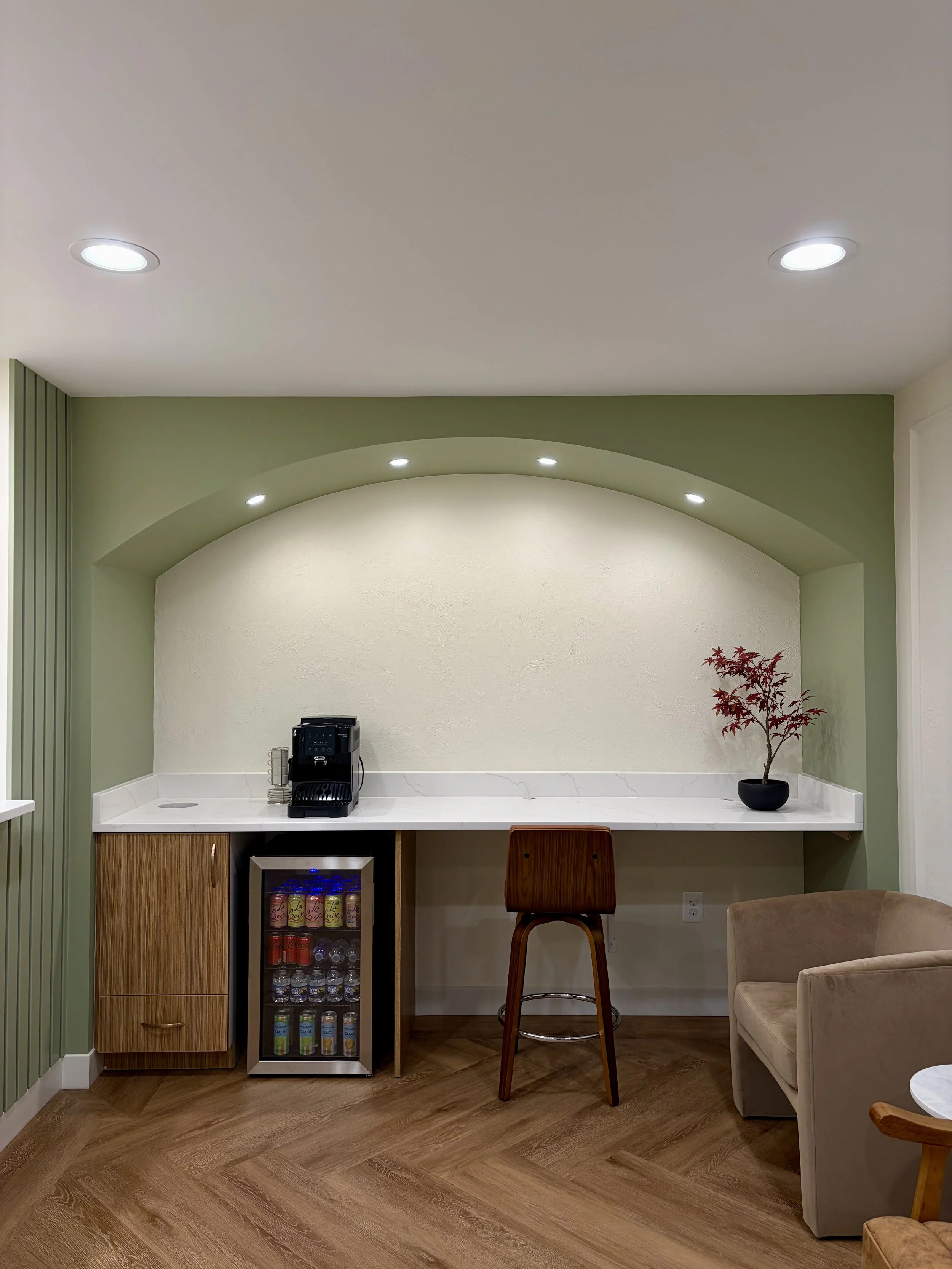 Dental waiting area with a quartz counter and beverage station highlighted by a green arch and vasari wall paint.