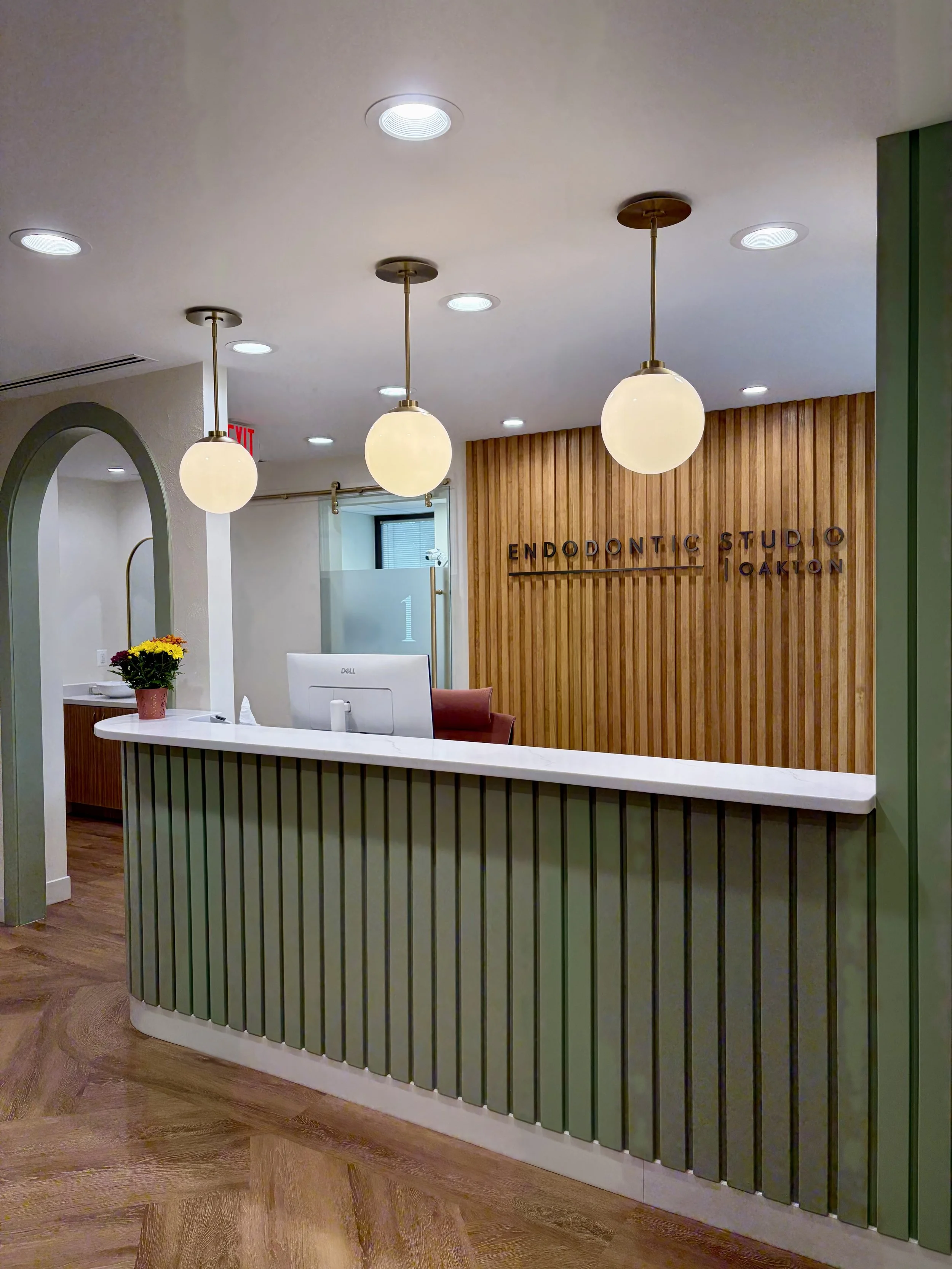 Dental Front Desk reception with quartz counter top, pendant lighting, and logo on the back wall highlighted by an arch door way