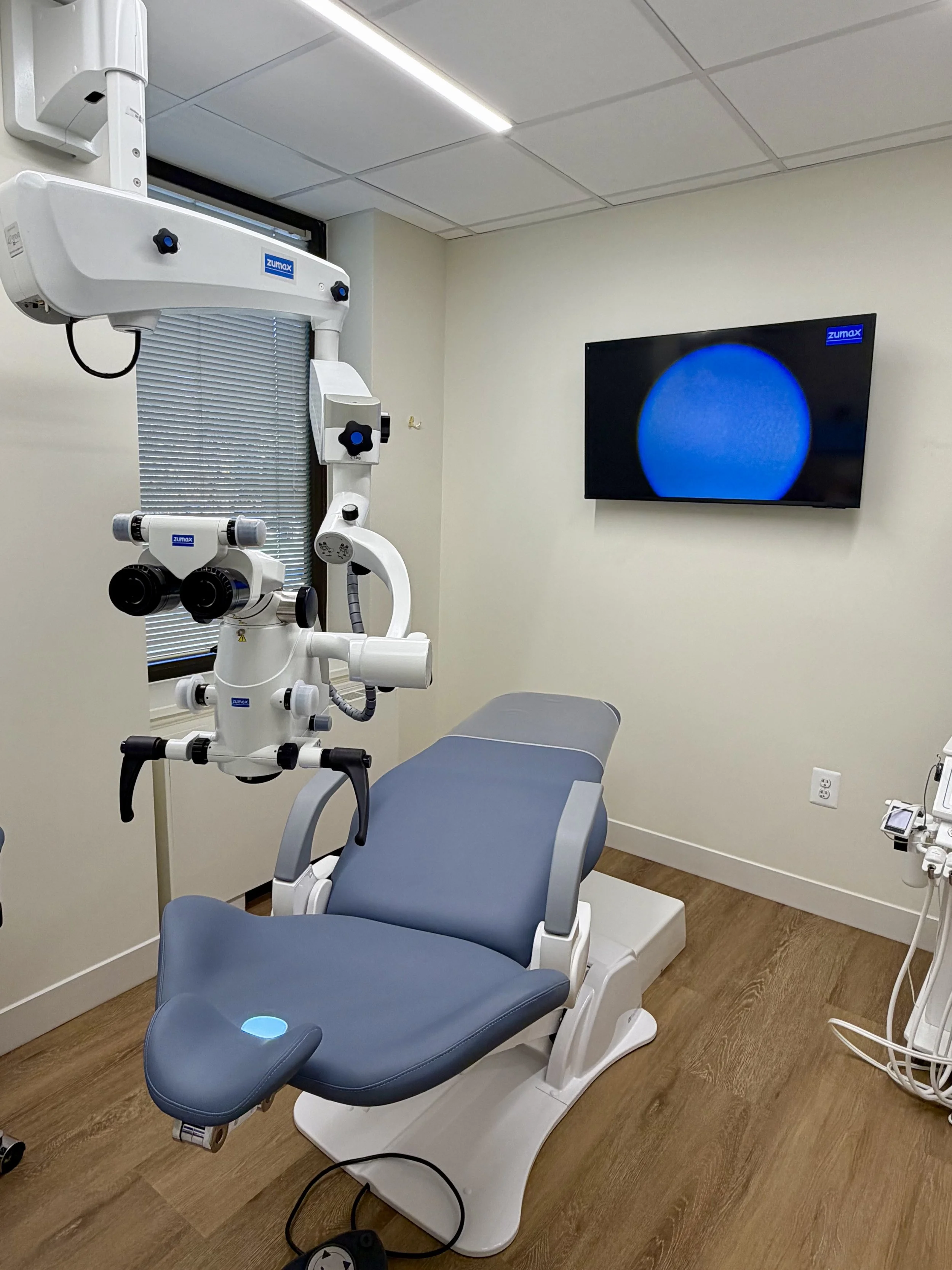 Dental Operating Microscope with camera setup projecting to the TV screen.