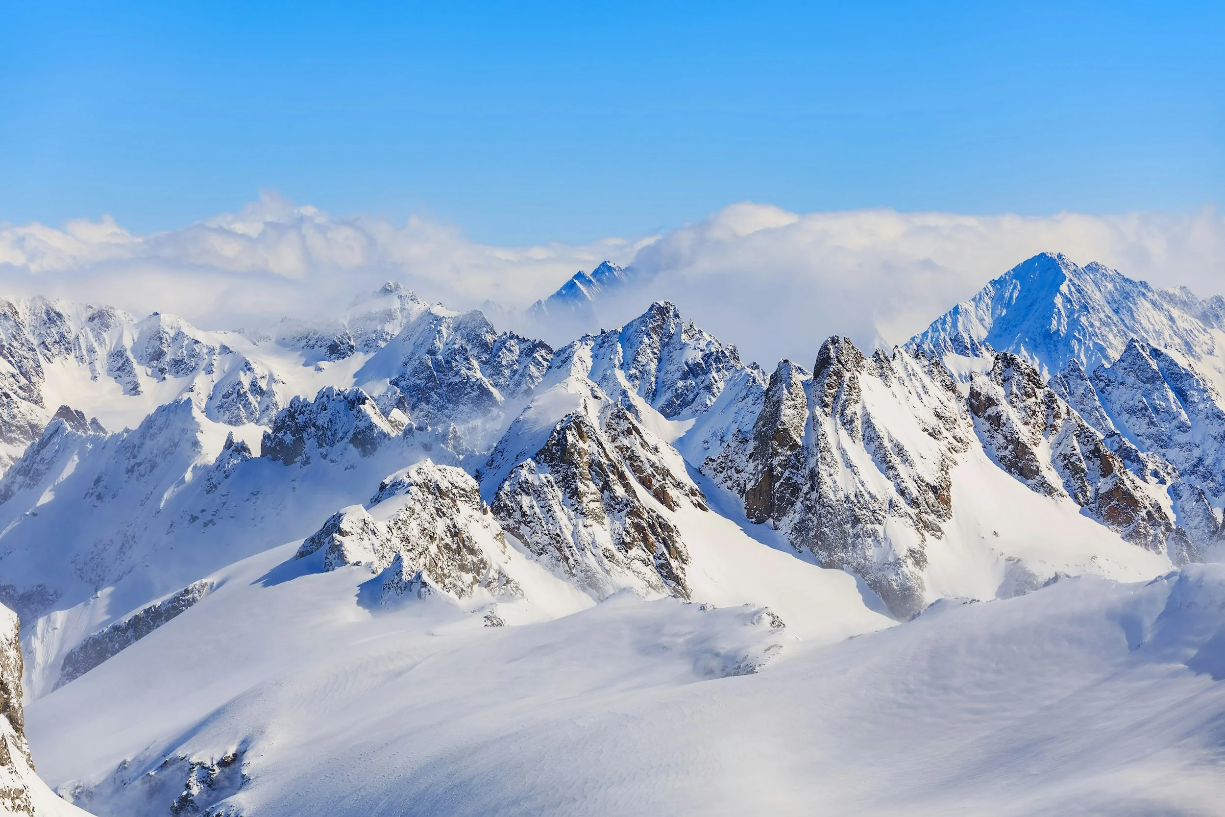 Snow-covered mountain range with sharp peaks under a clear blue sky