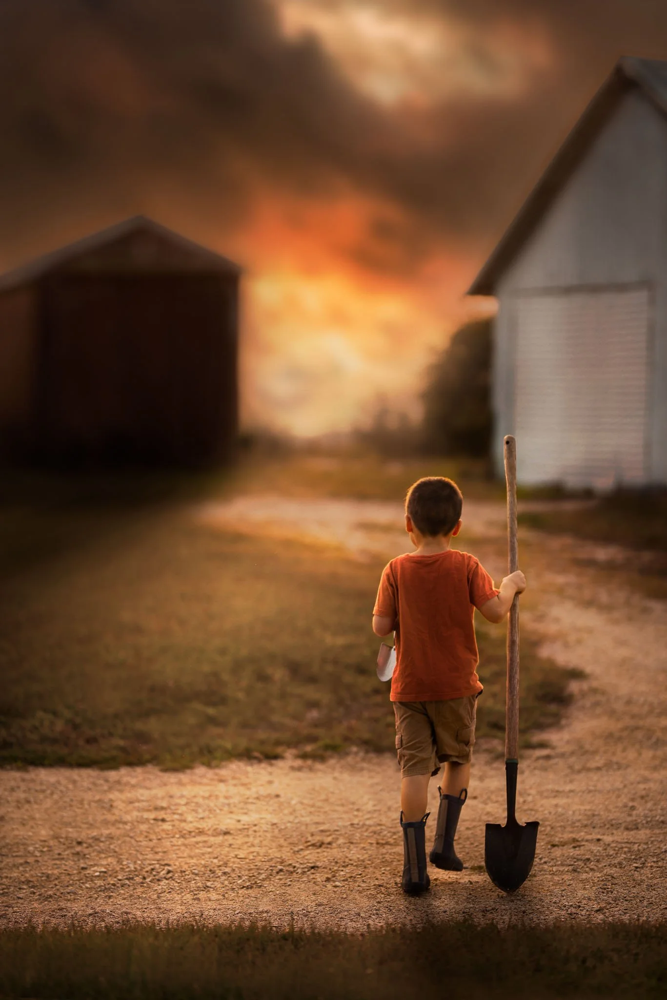 A young boy with crutches walking on a dirt road during a sunset, with houses and a fire in the background.