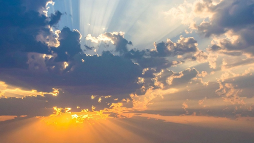 Sun rays shining through scattered clouds during a sunset or sunrise.
