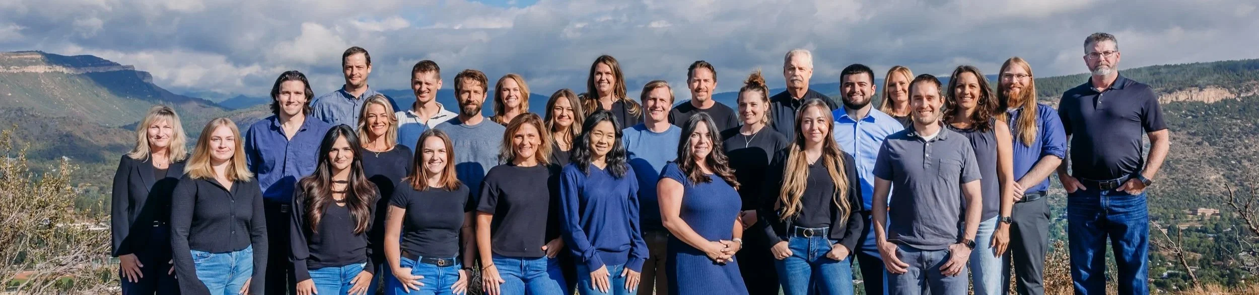 The Colorado Property Group real estate team standing together outdoors in Durango, Colorado with the San Juan Mountains in the background.