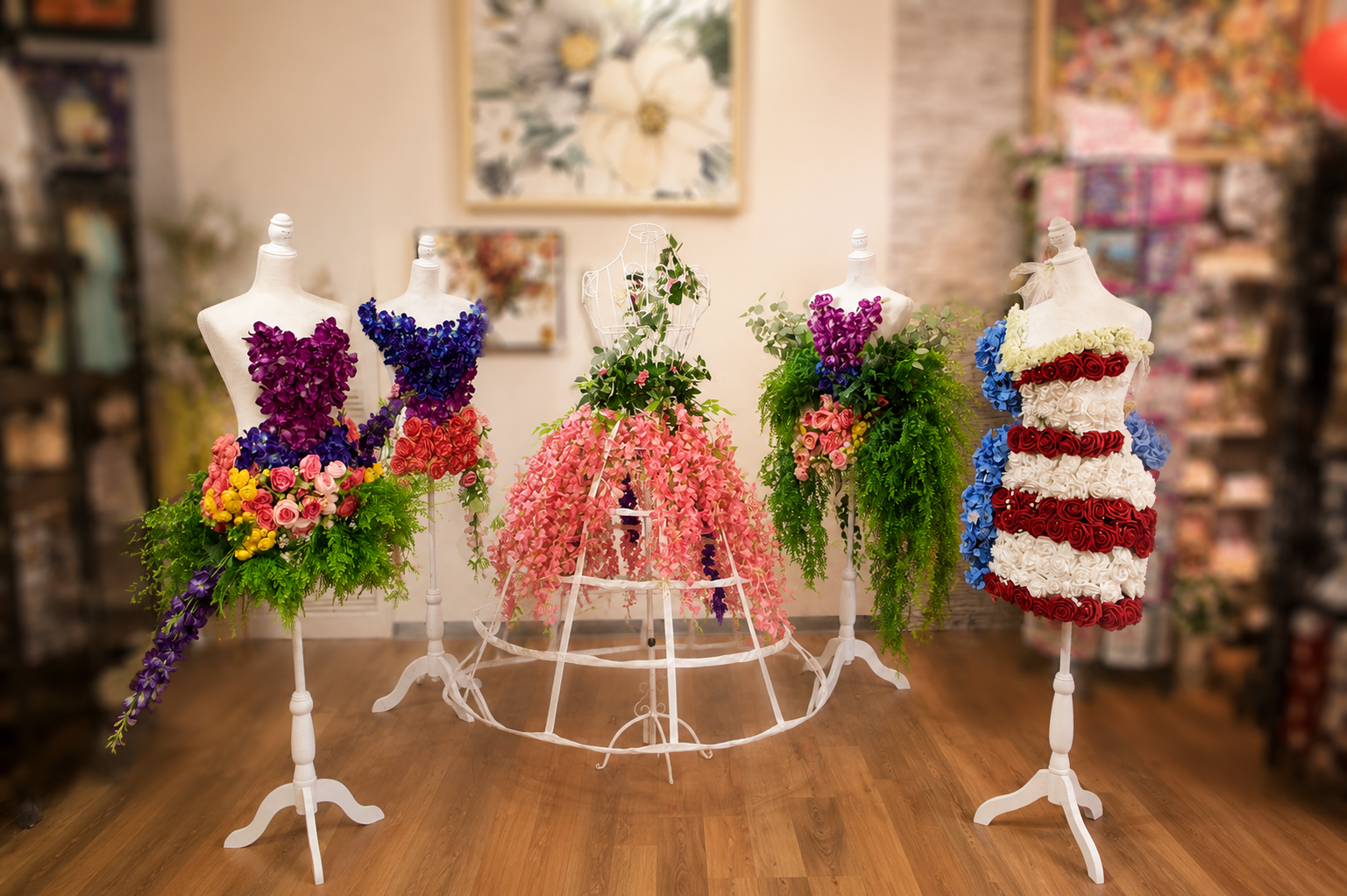 Artistic display of multiple floral mannequin dresses arranged in a boutique setting with decorative floral designs.