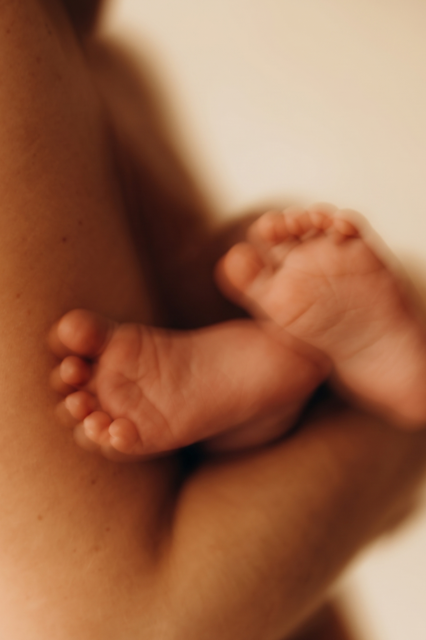 Close-up of a baby's tiny hand gripping a part of an adult's body, focusing on the hand with a blurred background.