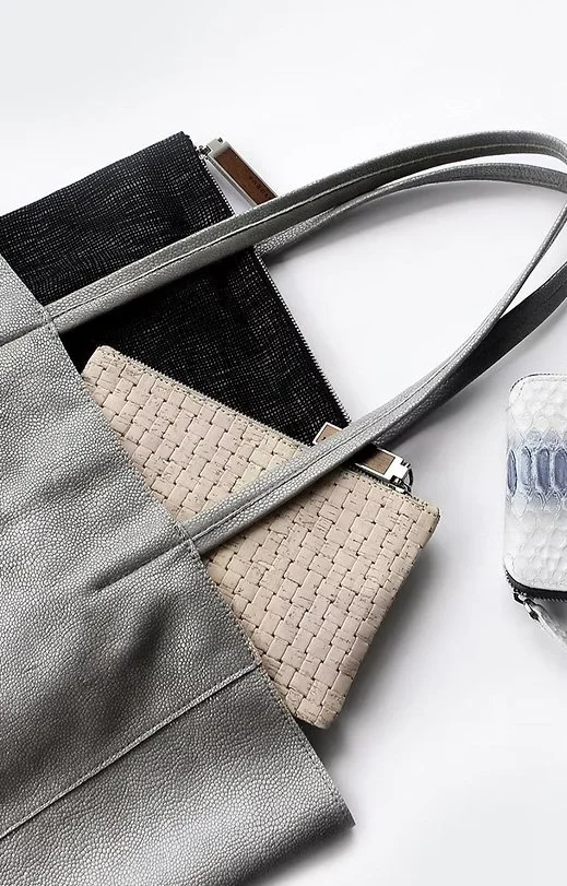 KAIA Consulting handbag design: Gray tote bag with two woven clutch purses inside, one black and one beige, and a partially visible wallet on a white surface