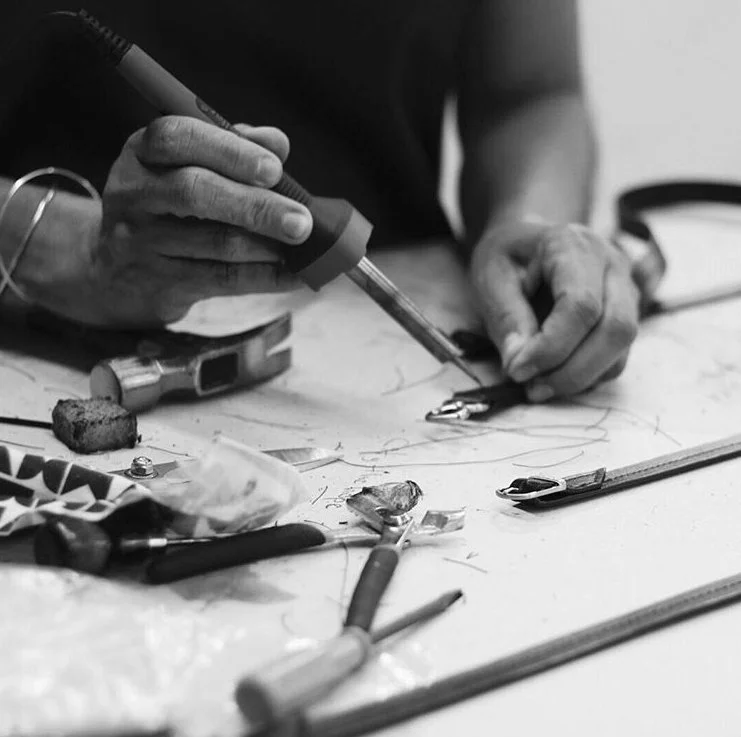 Woman working in artisanal handbag factory, making straps. Close up of hands.