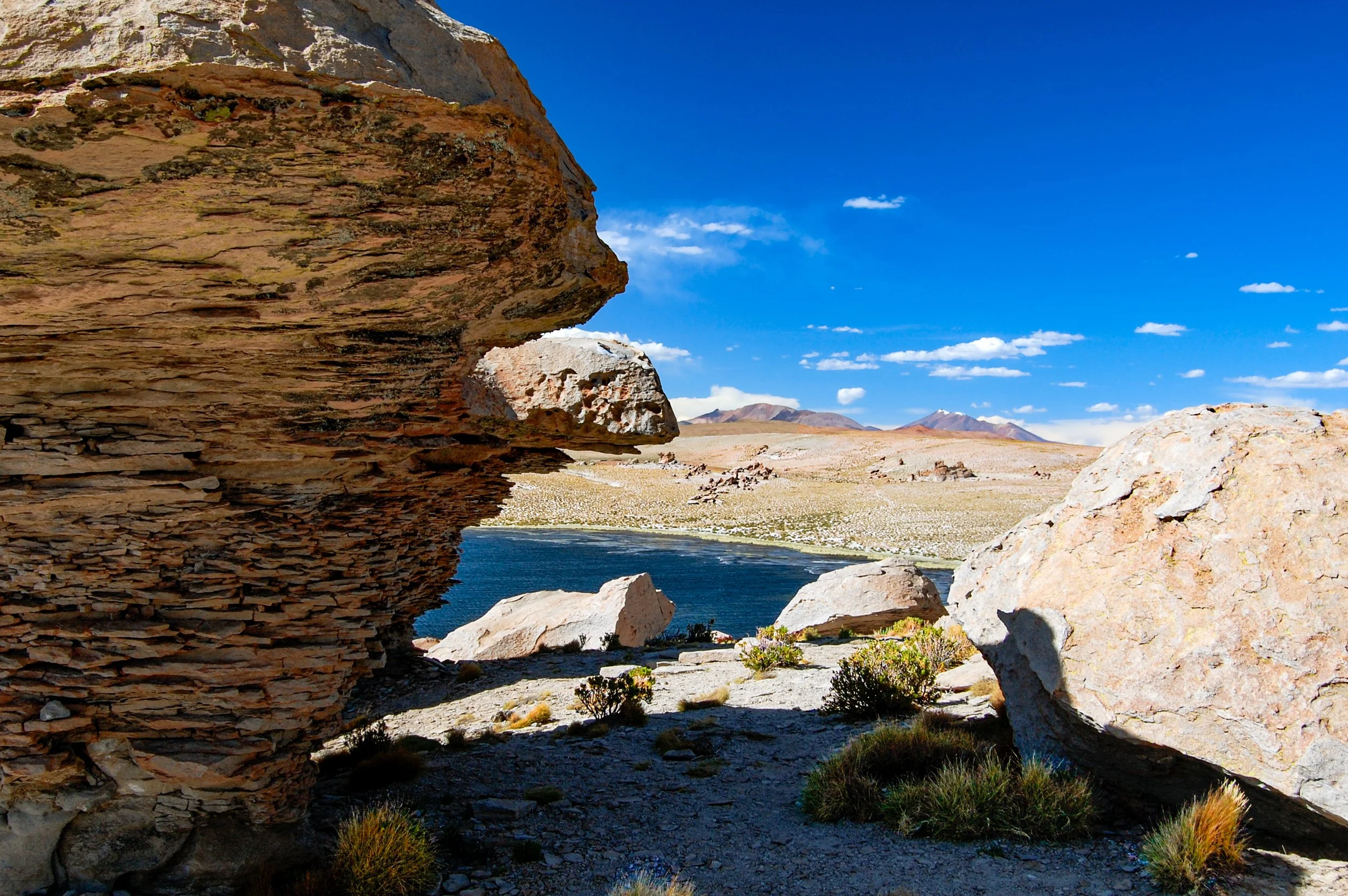 Een bergachtige landschap met grote rotsformaties, een rivier die door het gebied stroomt en een heldere blauwe hemel met enkele wolken.