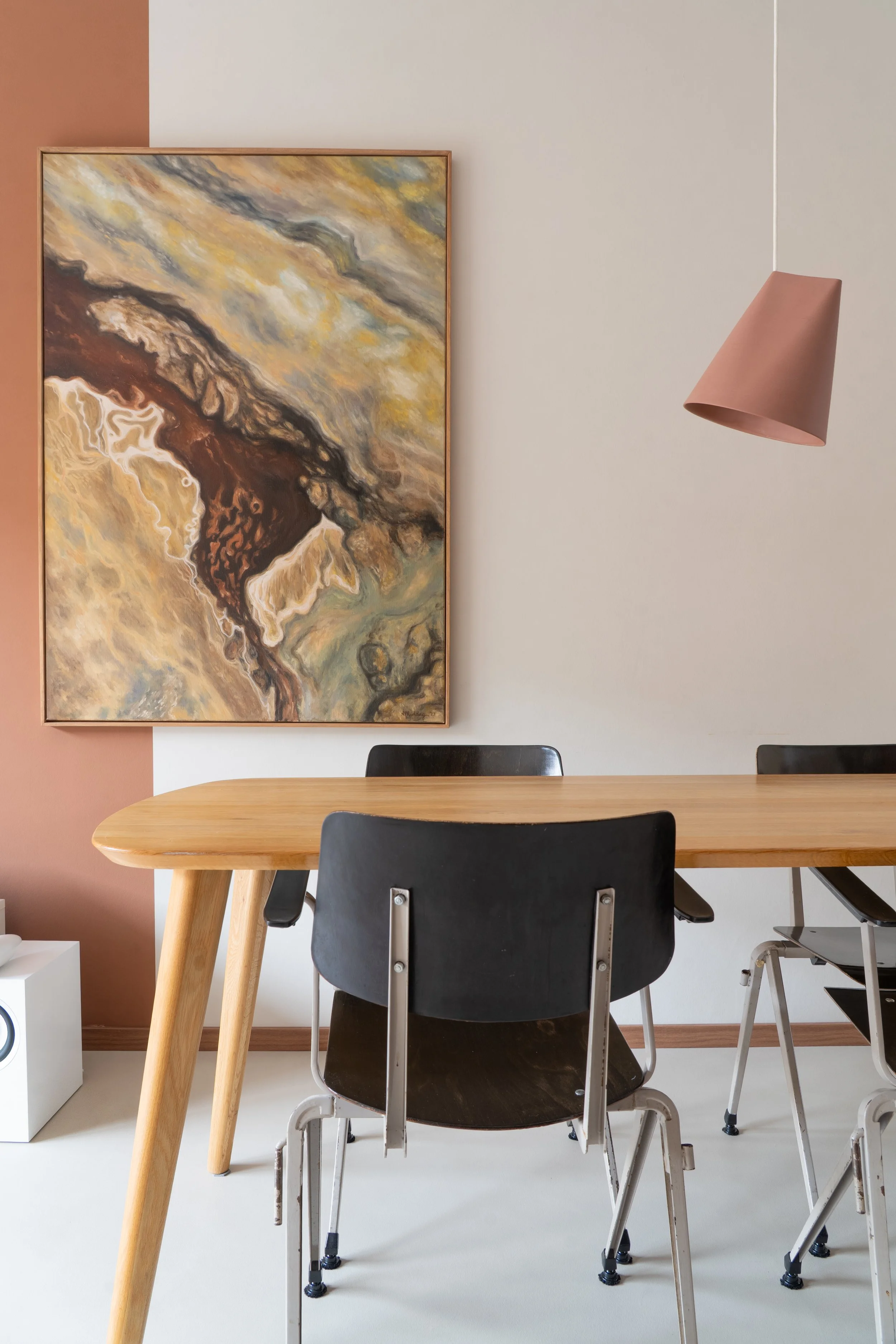 Een eetkamertafel met vier stoelen, een abstract schilderij aan de muur en een hanglamp.