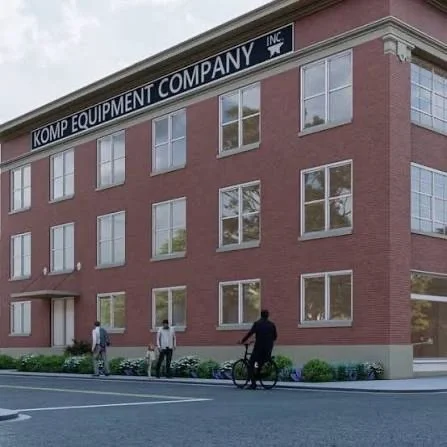 Three people standing outside a red brick office building with large windows, with one person on a bicycle, and signage reading " Equipment Company Inc."