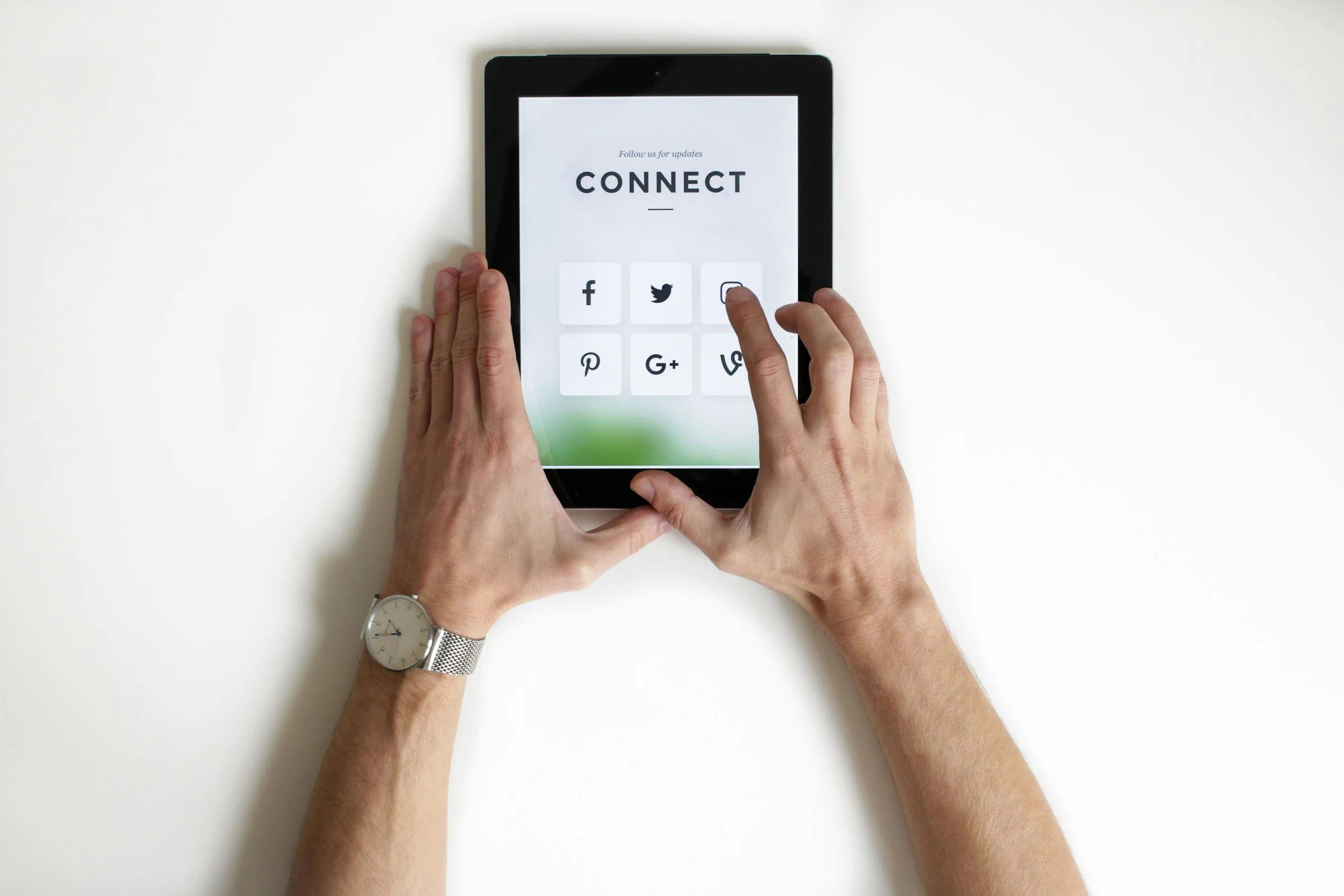 Person holding a tablet with social media icons on the screen, connected by the word "Connect" and a white background.