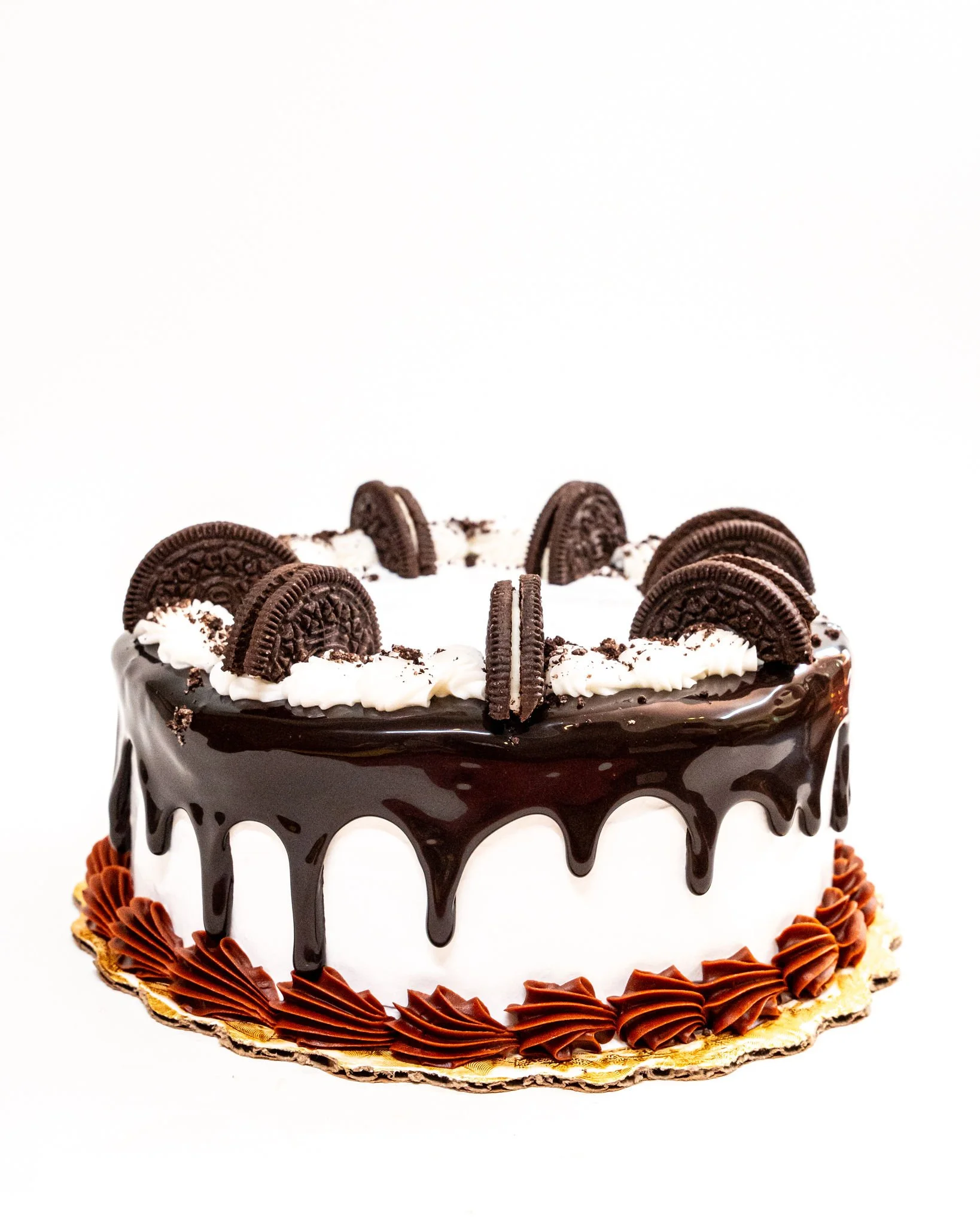 A round chocolate cake decorated with Oreo cookies on top and chocolate icing around the sides, with chocolate decorations at the base.