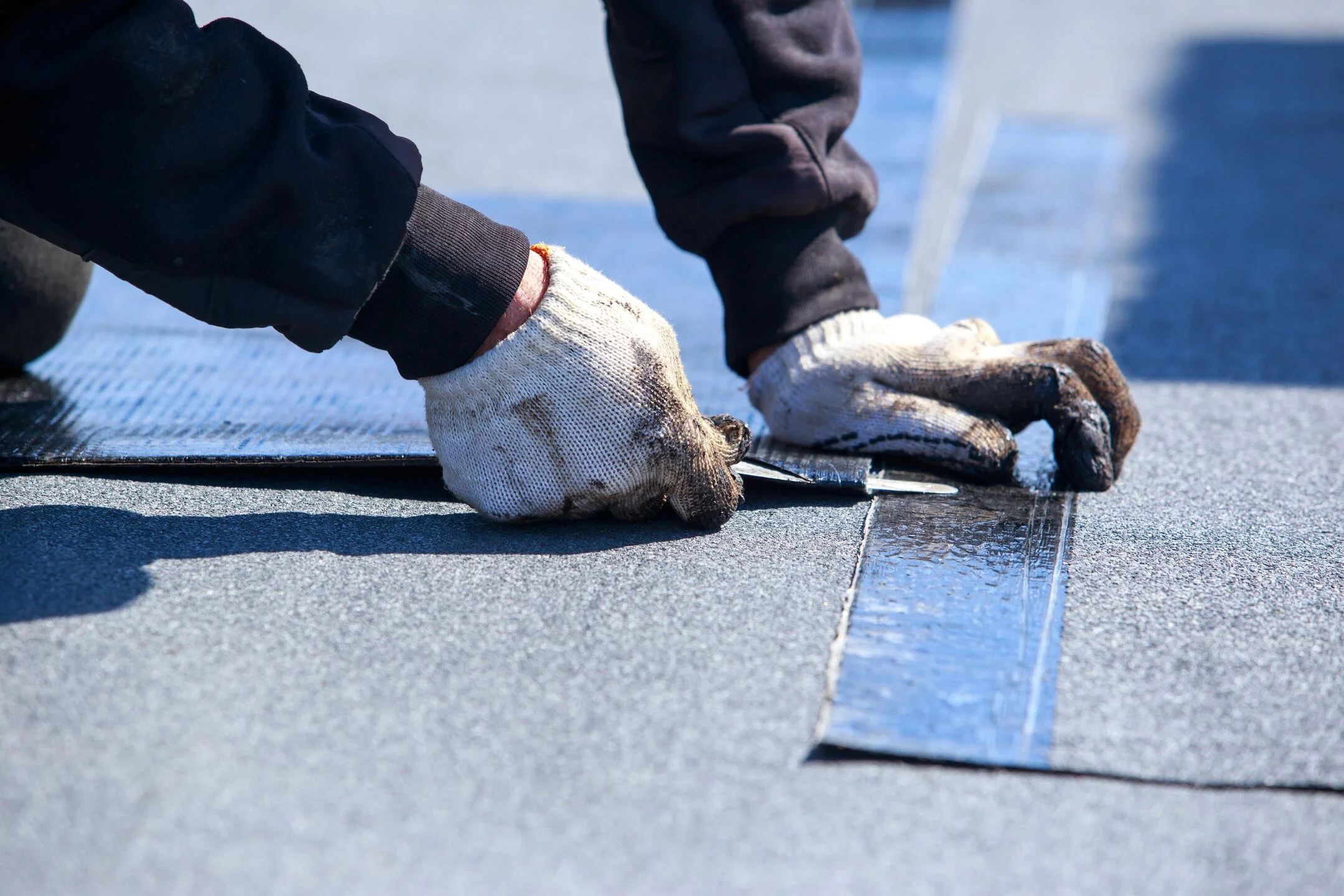 flat-roof-repair-close-up-of-gloved-tech-installing-new-section-of-flat-roofing-materials.jpg