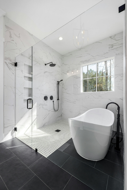 Luxury bathroom featuring a white freestanding tub next to a glass-enclosed marble tile walk-in shower.