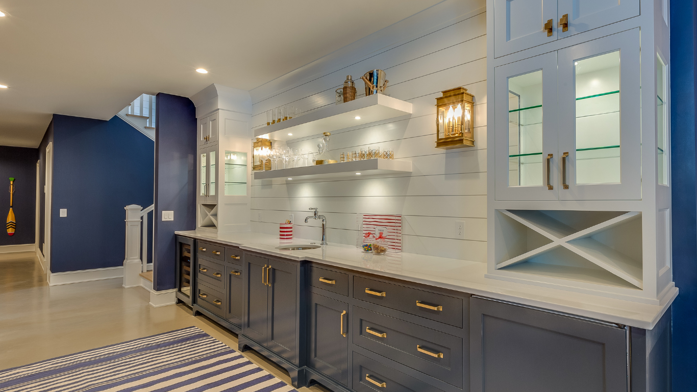 Modern basement wet bar featuring navy blue lower cabinets, white upper shelving, a white shiplap backsplash, and built-in wine storage.