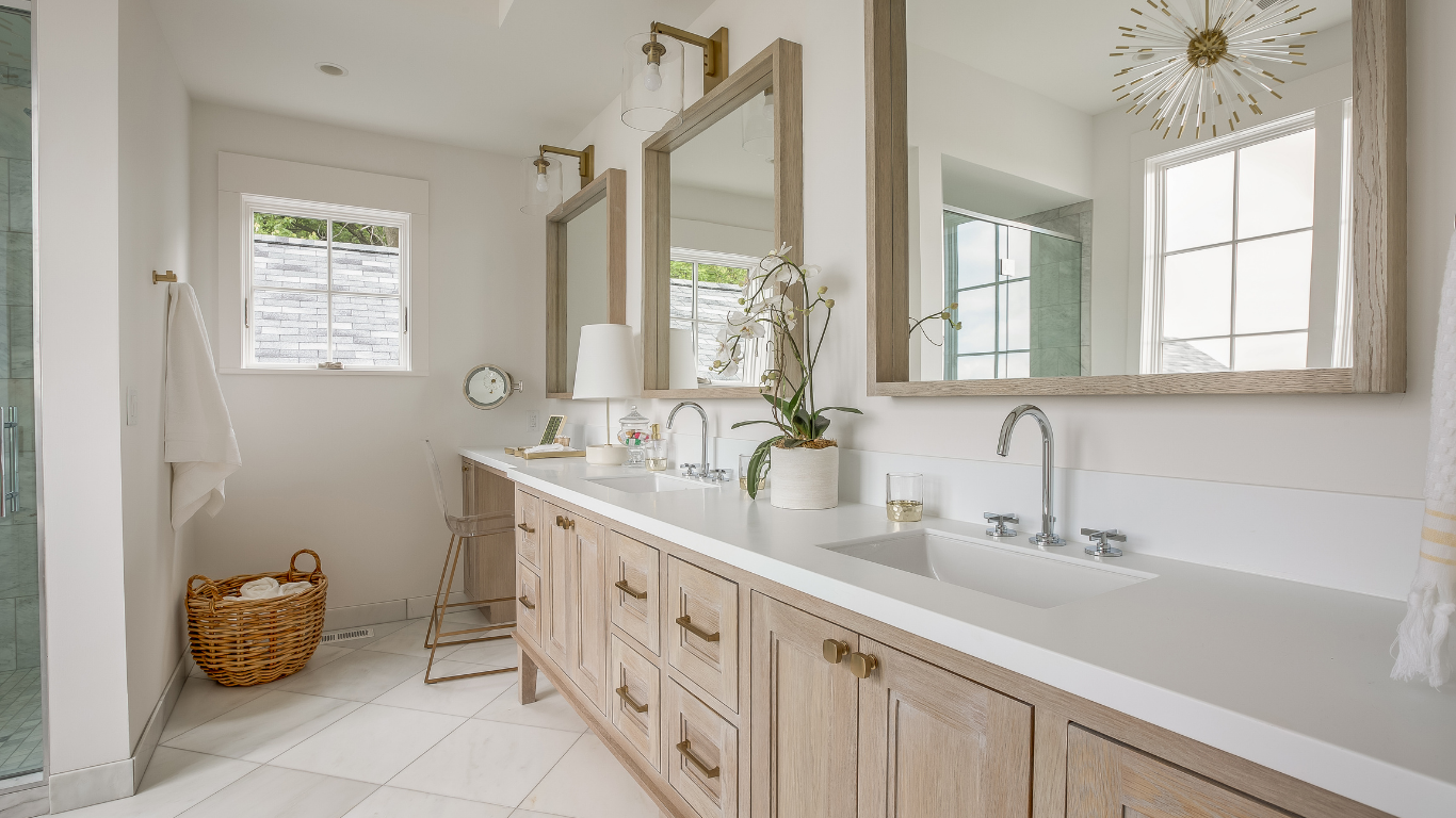 Bright bathroom featuring a long light-wood double vanity with white countertops, three large square mirrors, and gold hardware.