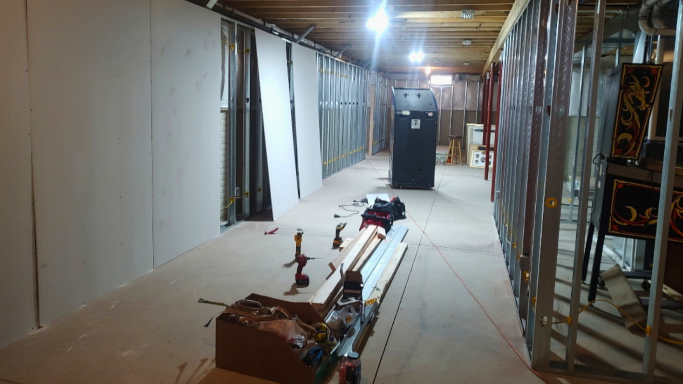 Interior of a building under construction with unfinished walls, tools, and equipment scattered across the floor.