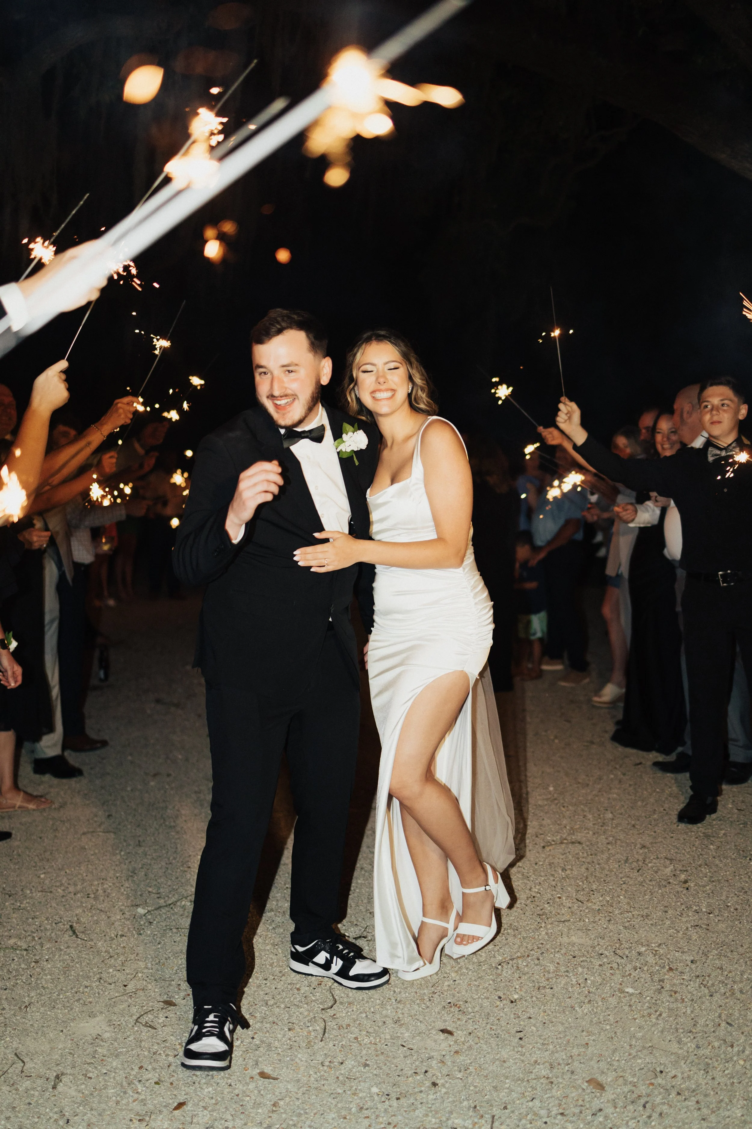 Celebrating a wedding at night with a couple dancing among guests holding sparklers.