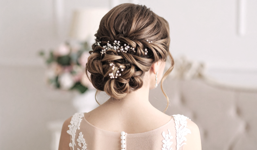 Back view of a woman's updo hairstyle with decorative hair accessories, wearing a wedding dress.