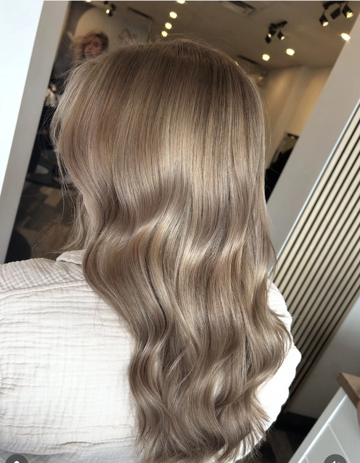 Woman with long, wavy, light blonde hair in a salon.