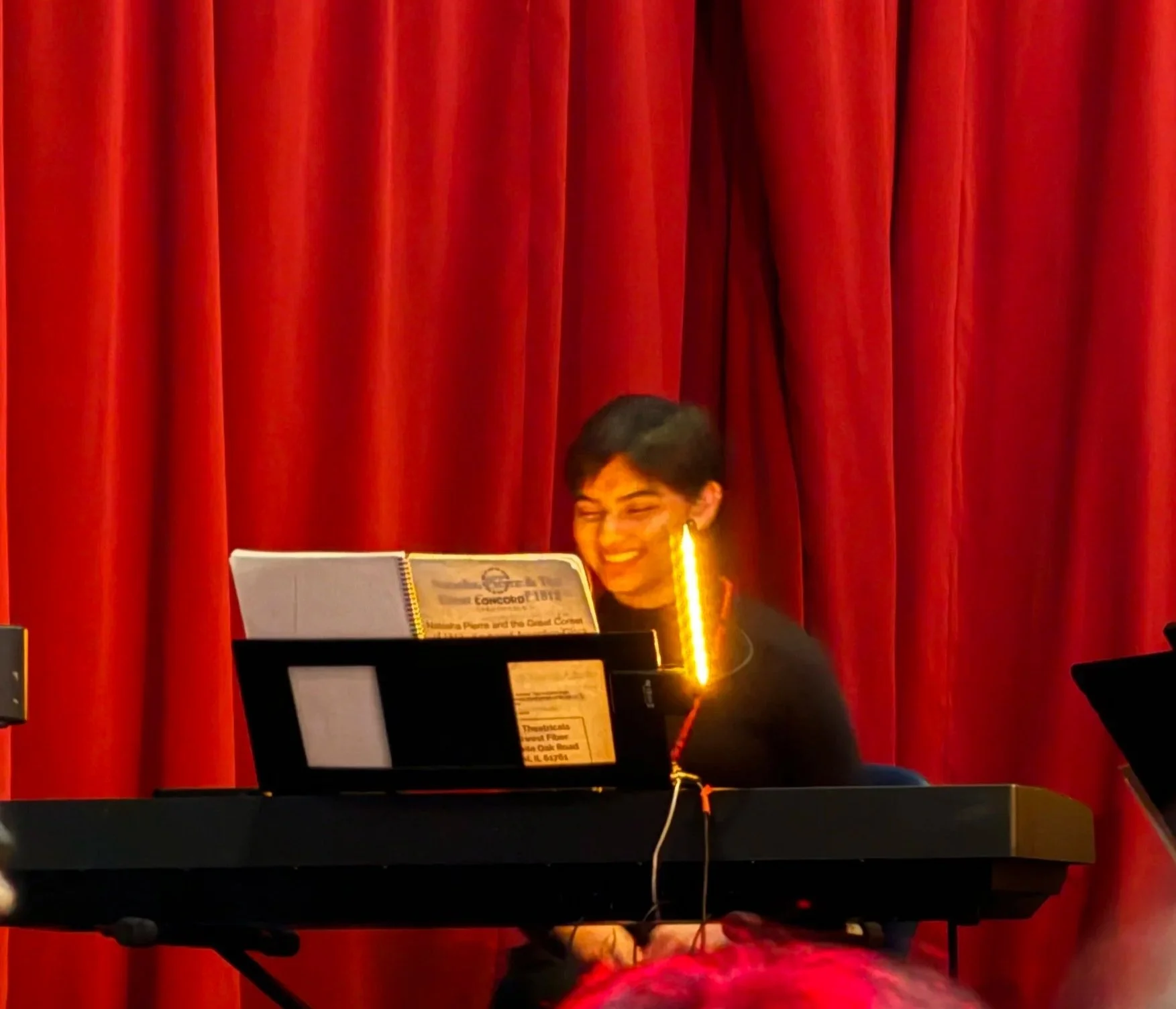 Image of Valerie playing keyboard in college production of a musical