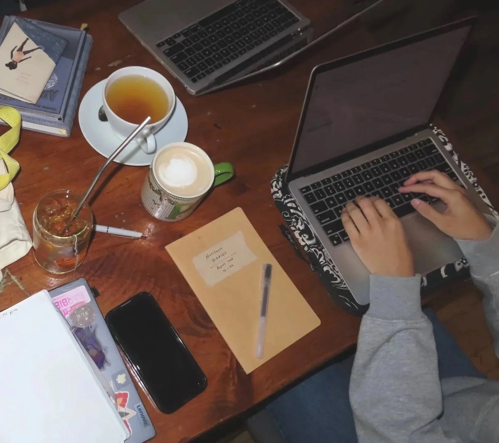 Image of laptop, notebook, and tea against a wooden table