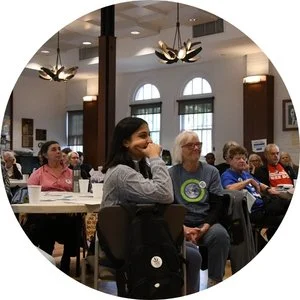 Photo of a diverse room of people listening to a presentation.