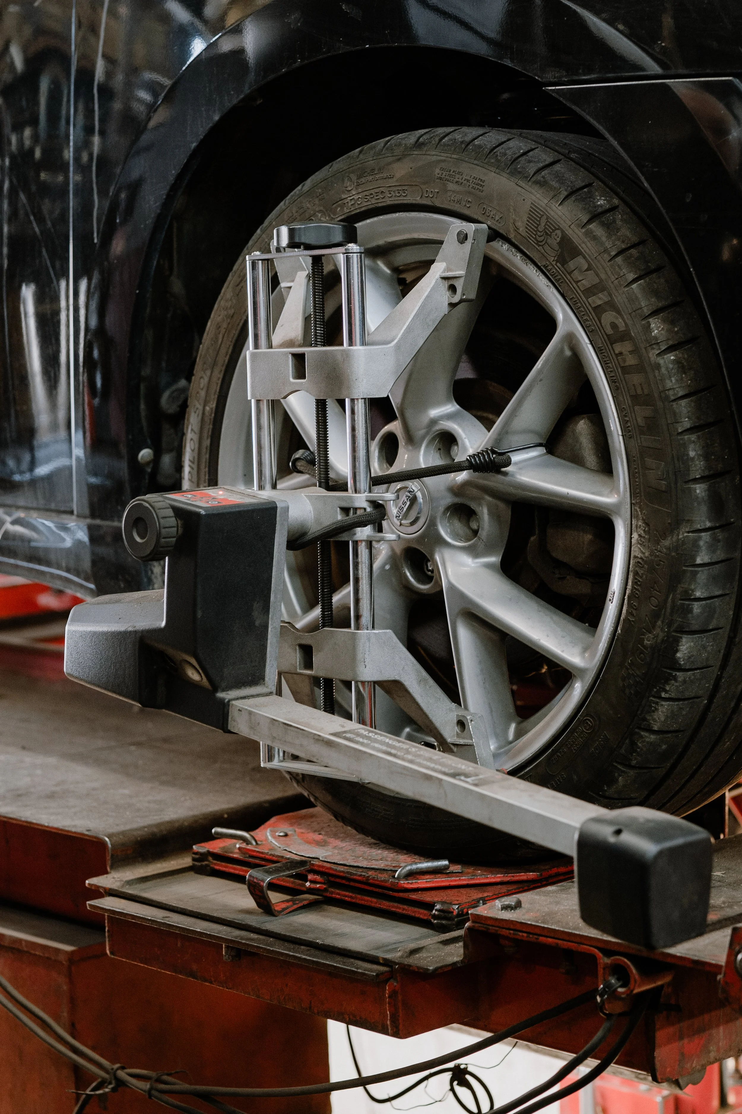 A wheel alignment machine being used on a car tire in an auto repair shop.