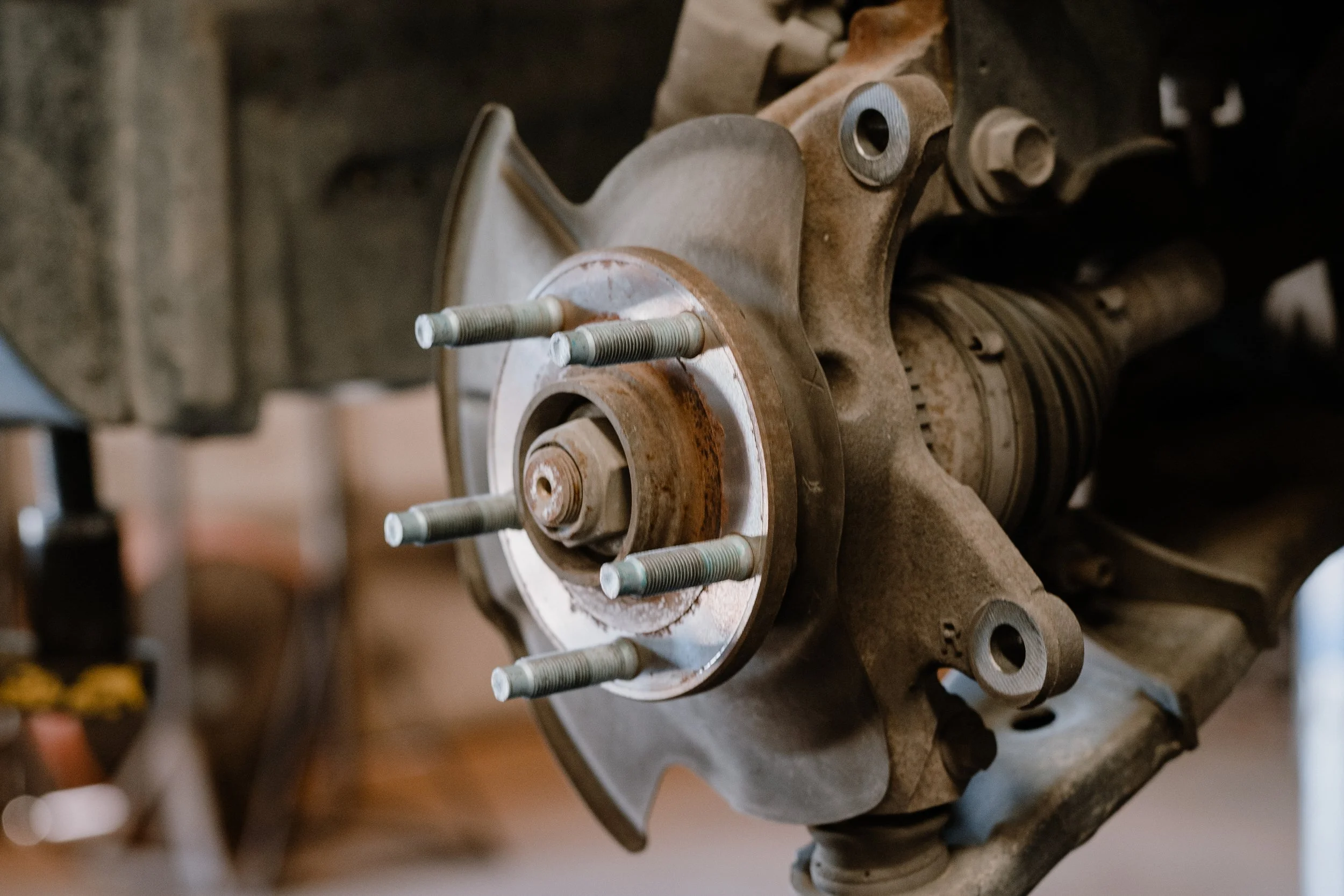 Close-up of a rusty car wheel hub with lug bolts and part of the brake disc visible.