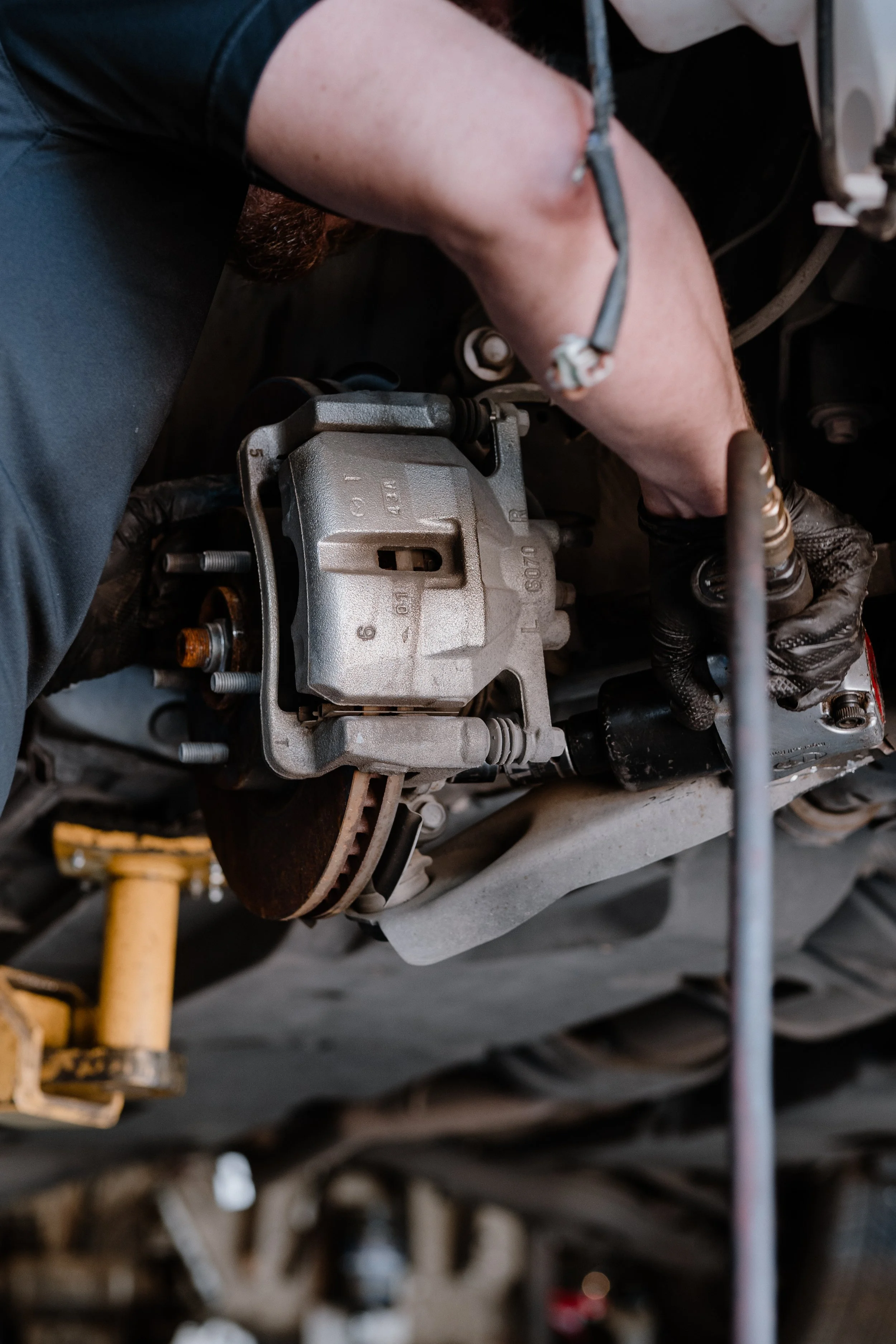 A mechanic's arm working on a car's engine, with tools and mechanical parts visible.