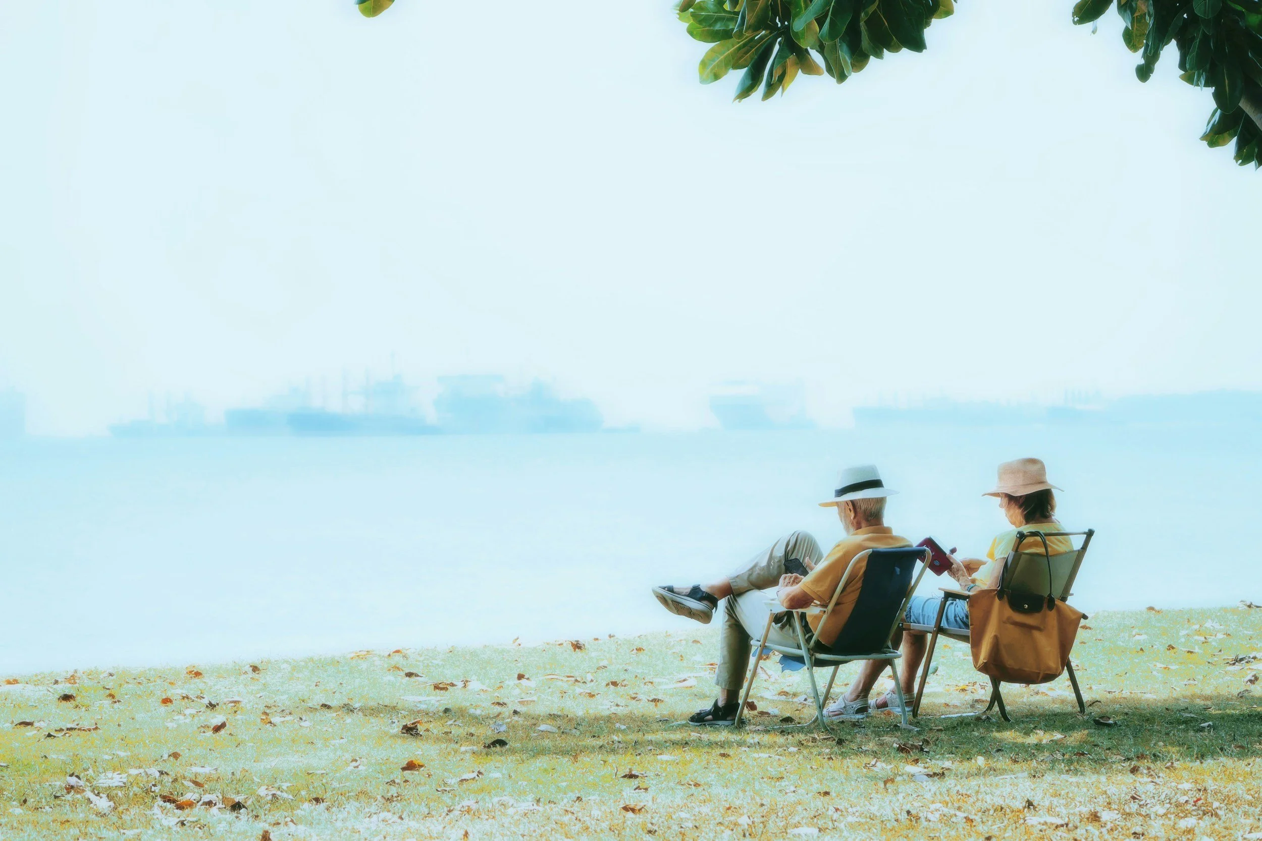 a couple sitting in their portable chairs, reading on the beach reading.