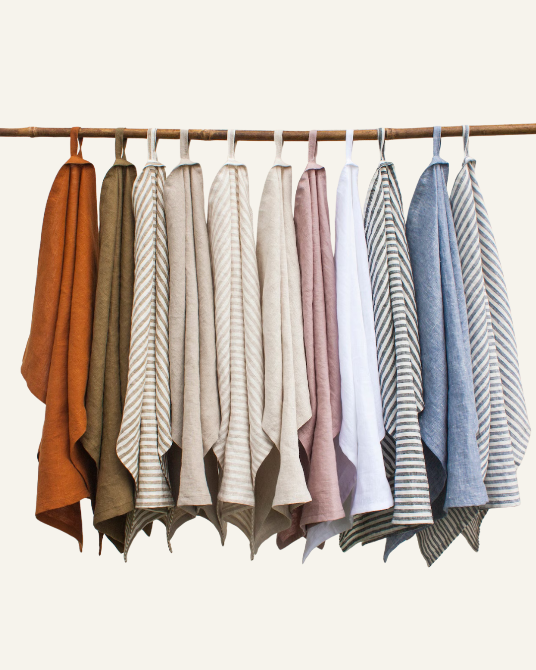 several multi coloured linen tea towels hanging by loop on a branch