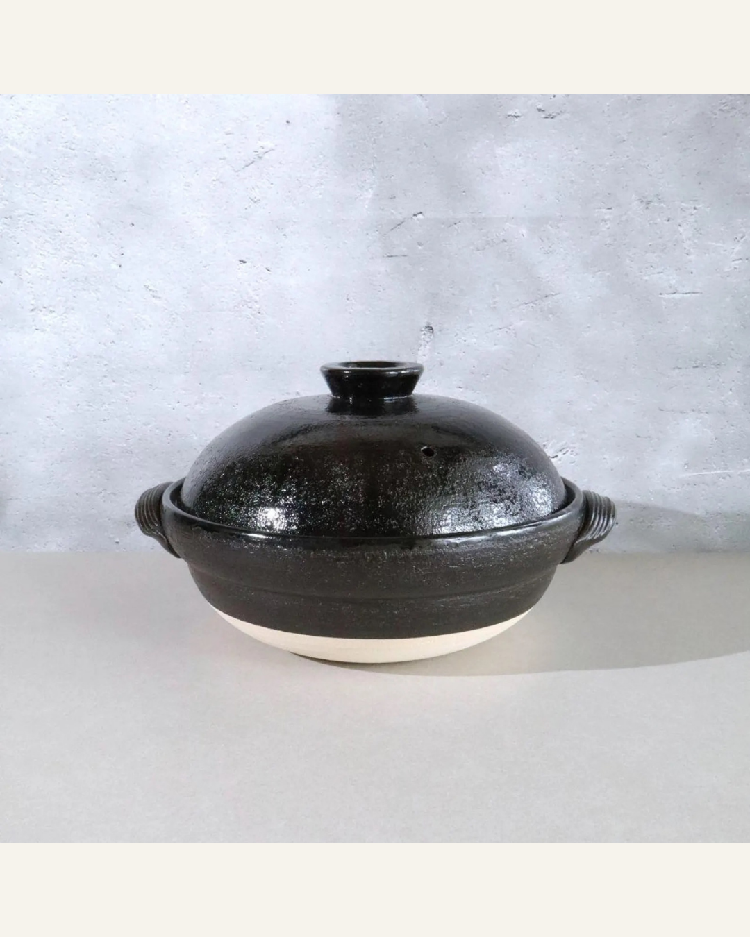 a black clay Donate pot with beige bottom