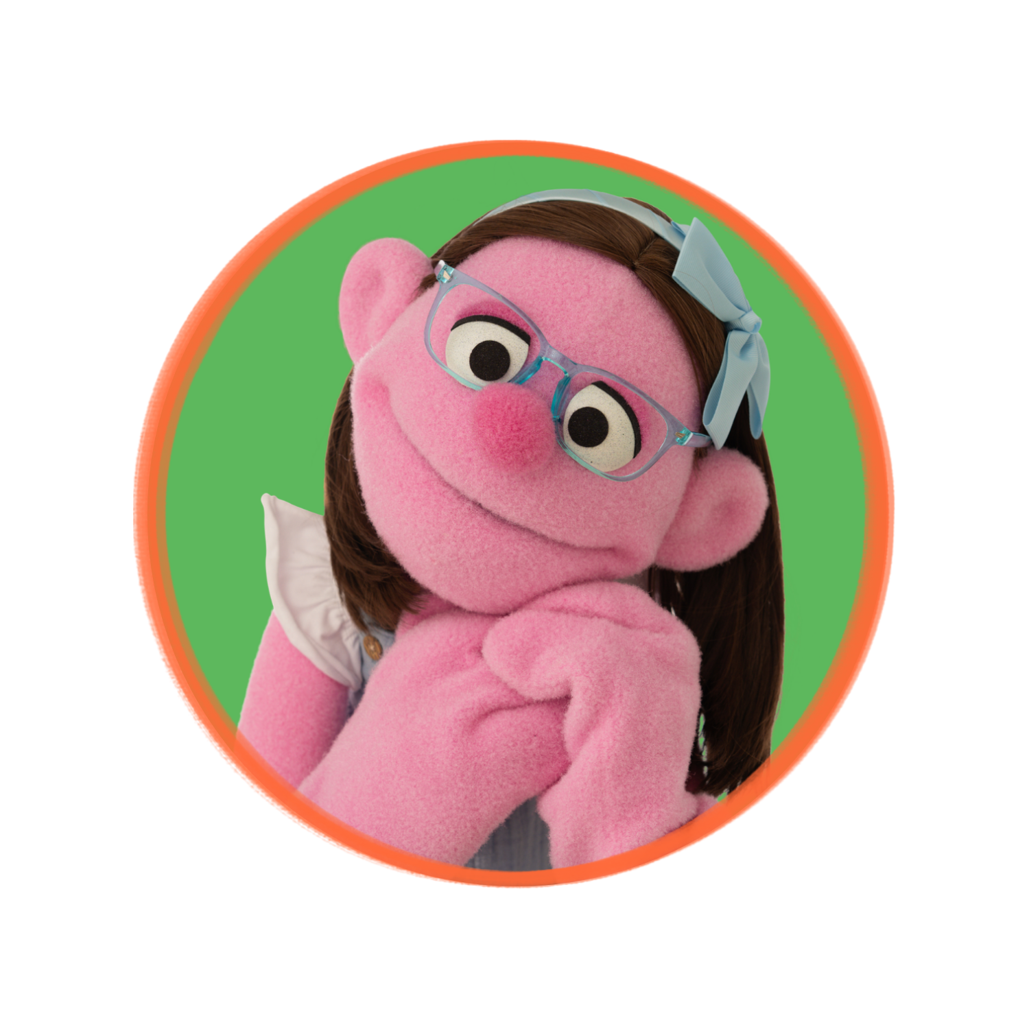 A person dressed as a pink puppet character with glasses, brown hair, and a blue bow, resting her chin on her hand with a playful expression, against a green background with a circular red and orange outline.