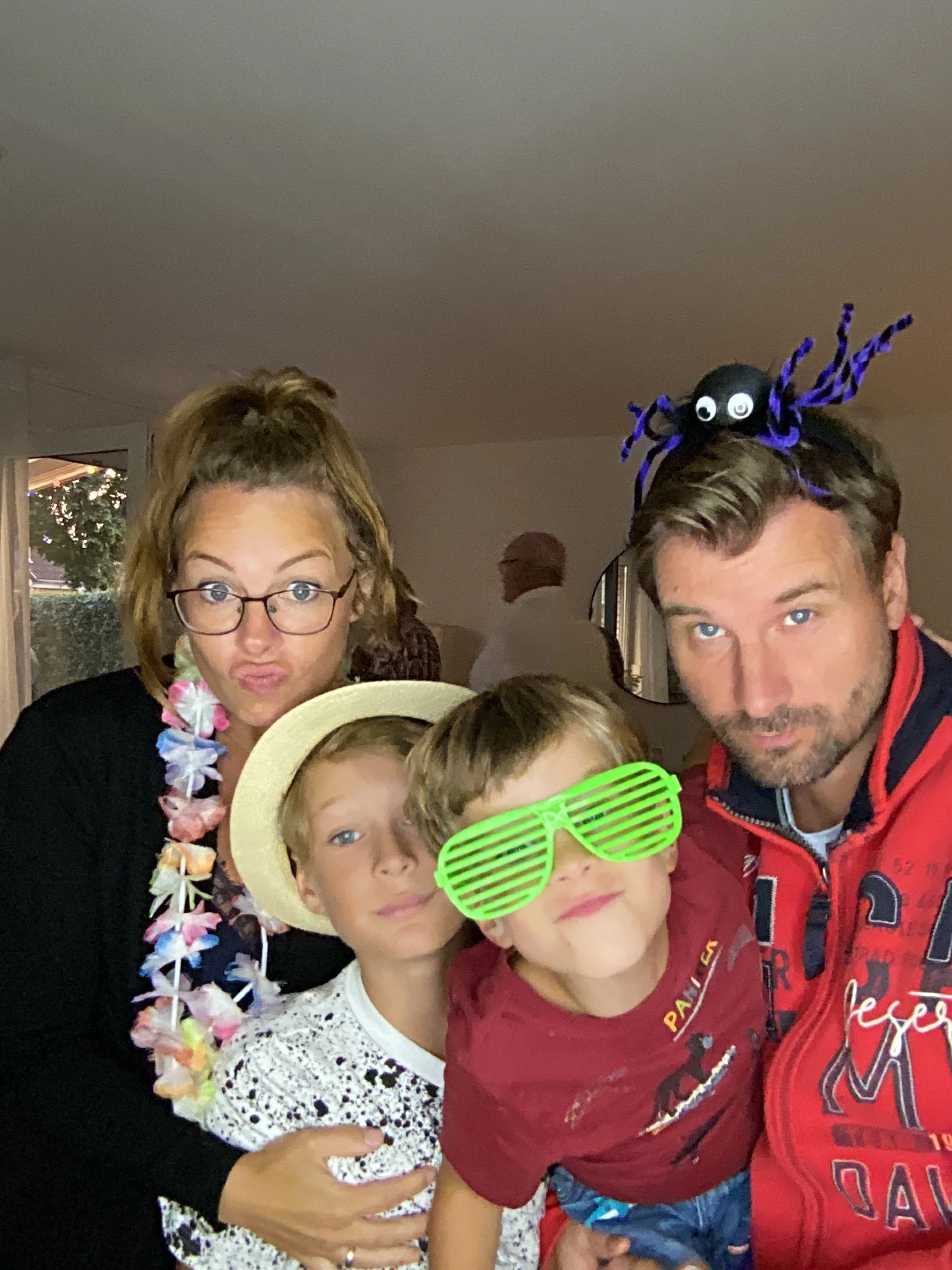 Familie bei einer Feier, mit Sommerkleidung, Party-Accessoires wie Brille und Halsketten und machen ein Foto vor der Fotobox.