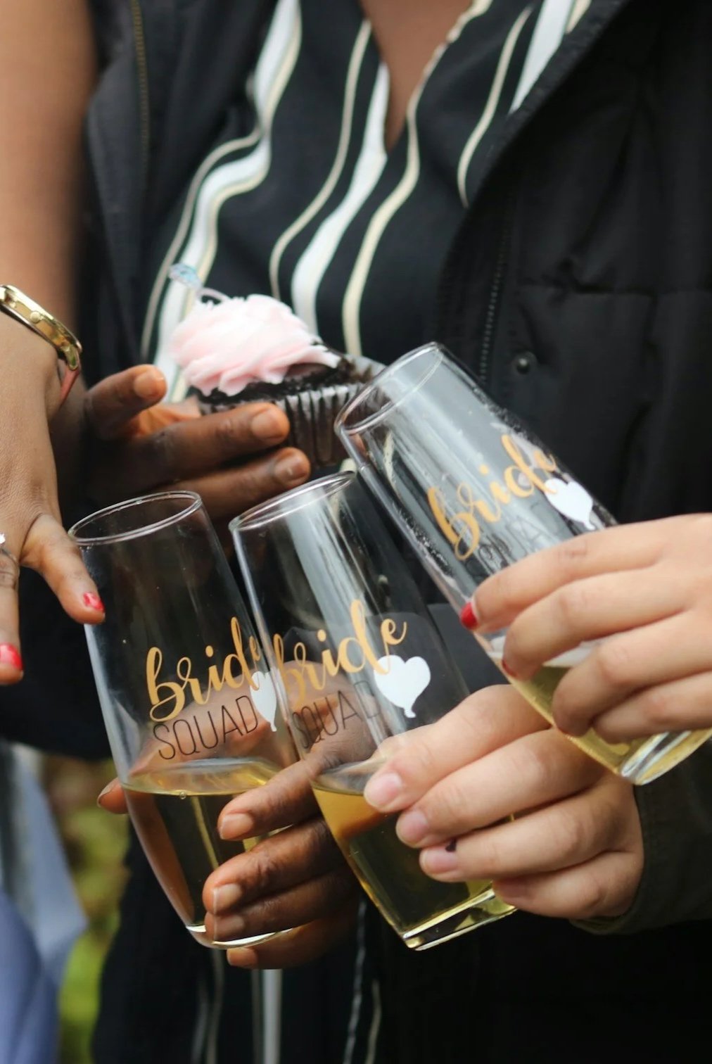 Multiple women holding wedding glasses with the words 'bride squad' and a heart, celebrating a bridal shower or bachelorette party.