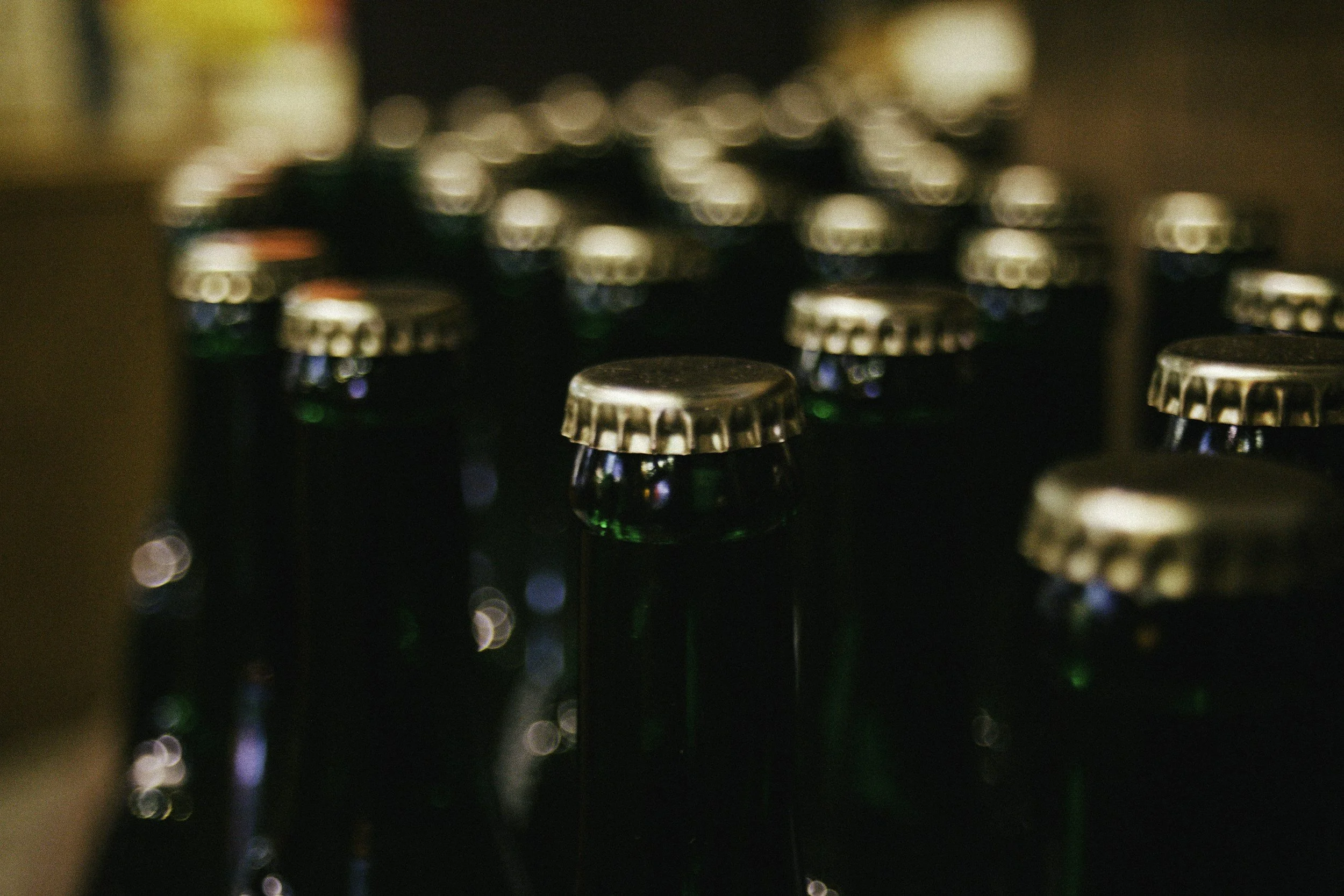 Close-up of multiple glass bottles with metal caps arranged closely together, out of focus.