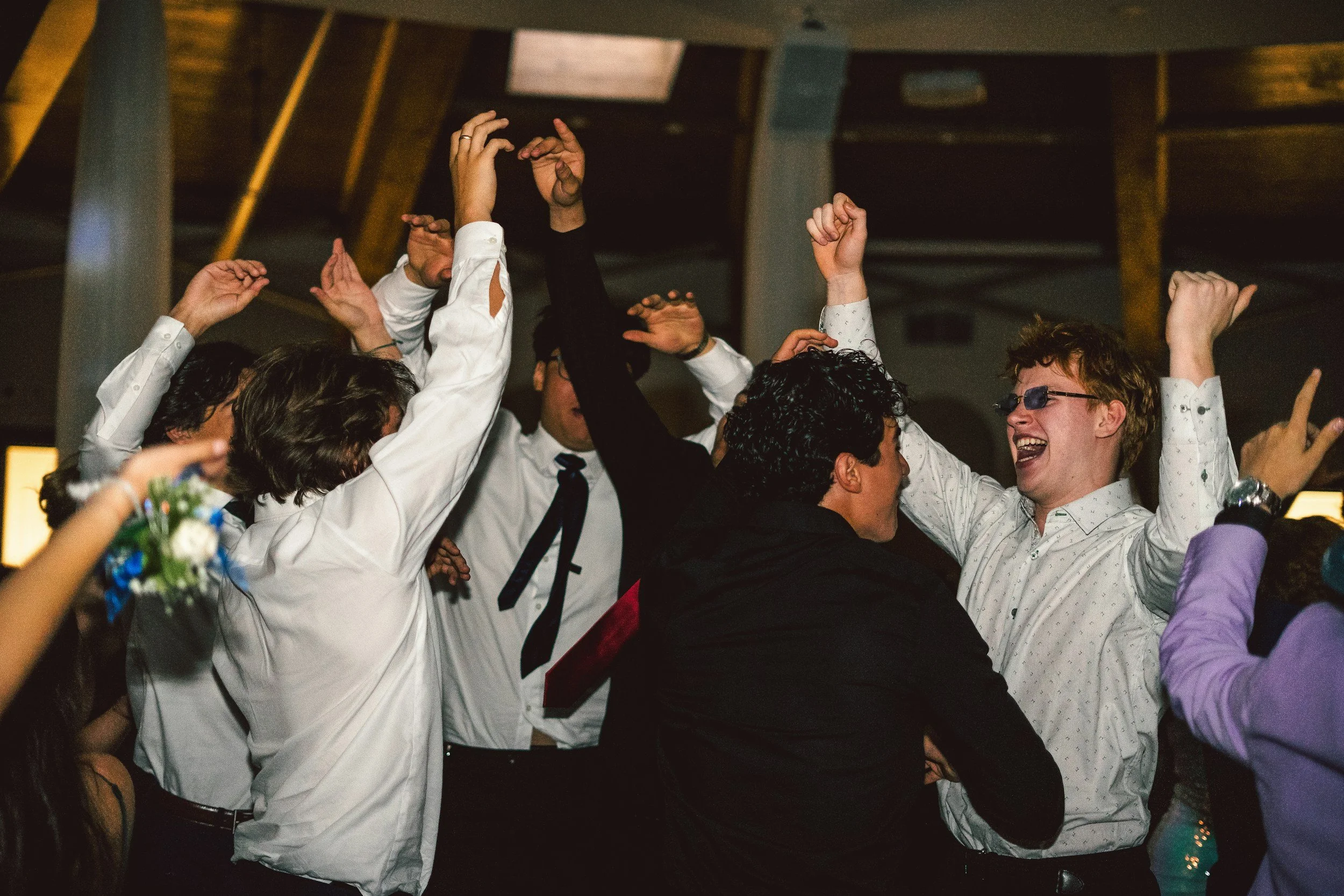 People celebrating and dancing indoors, with raised hands and smiling faces.