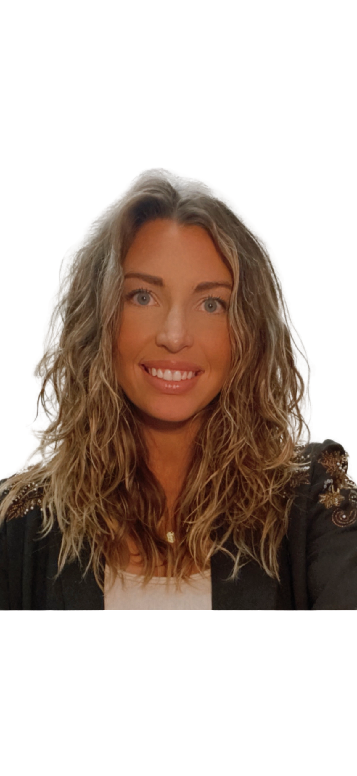 A woman with wavy blonde hair, blue eyes, and a bright smile, wearing a black jacket with glittering gold embroidery and a white top.