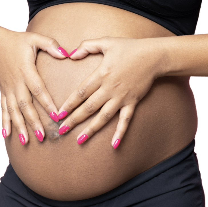 Close-up of a pregnant woman's belly with hands and fingers forming a heart shape on her stomach, nails painted pink.