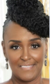 Close-up of a smiling Black woman with natural curly hair styled in an updo, wearing earrings and makeup.
