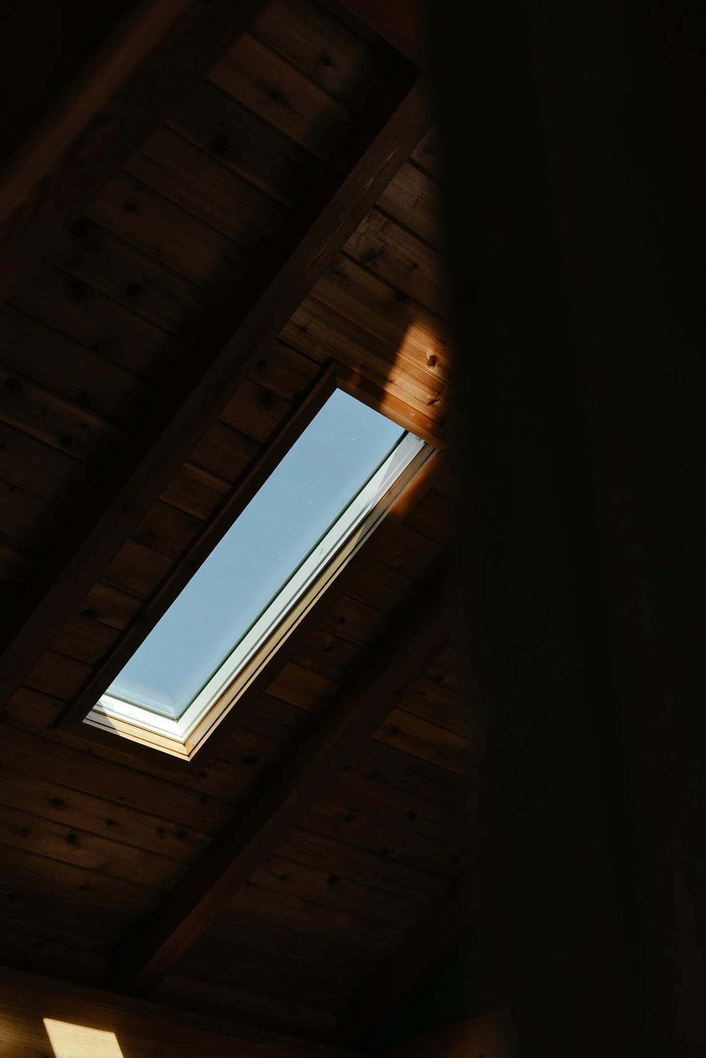 A skylight window in a wooden ceiling, allowing natural light to illuminate the space.
